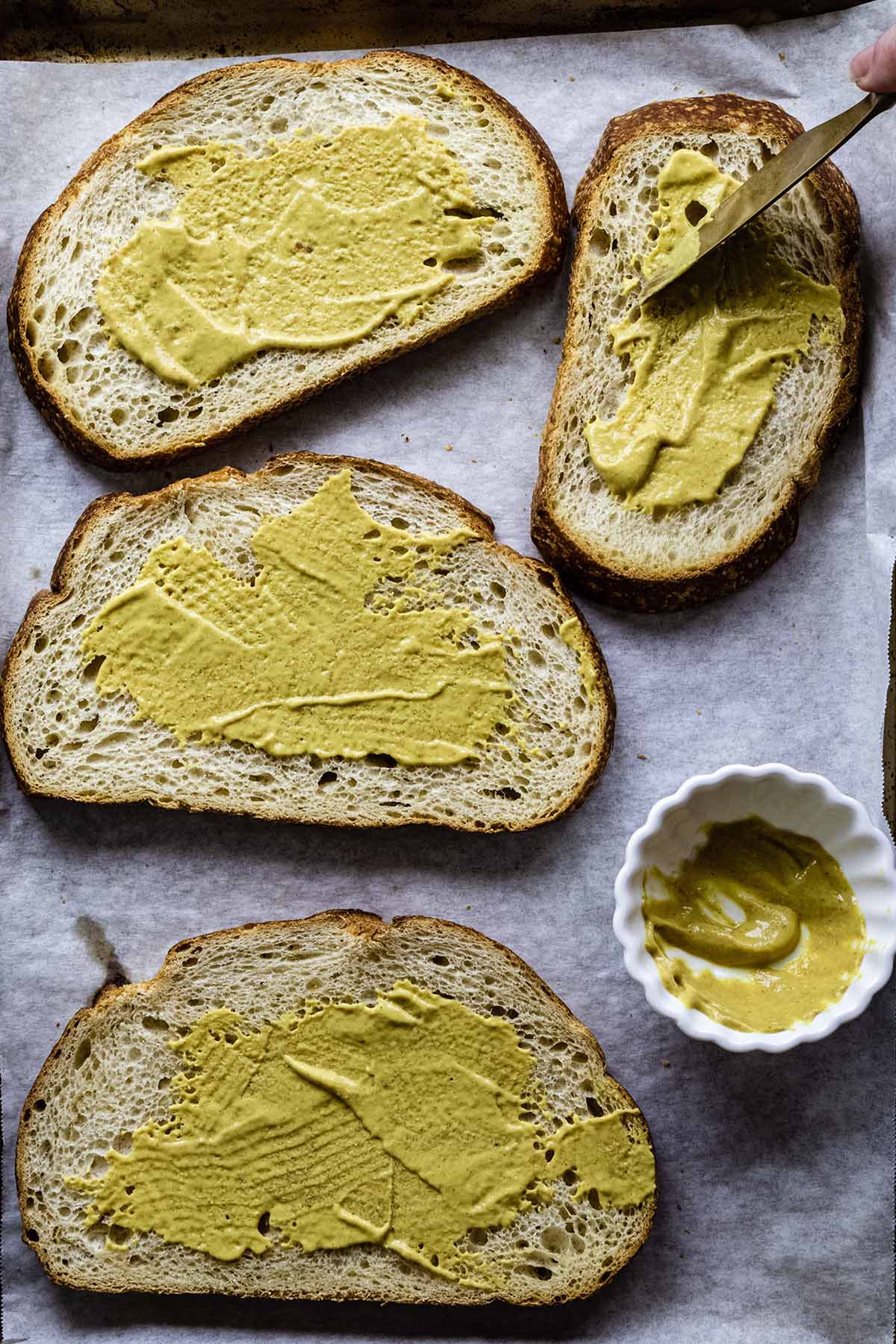 Spreading mustard on four slices of bread