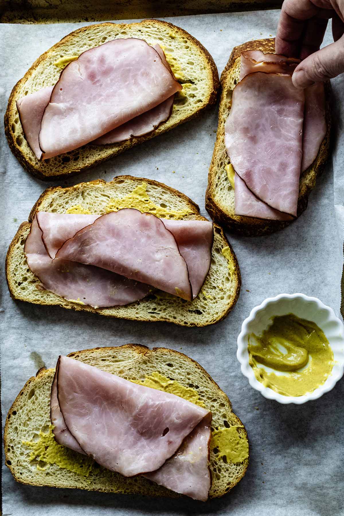 Placing ham slices on four sandwiches