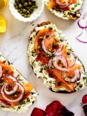 Overhead of smoked salmon toasts with lemon, capers and red onion