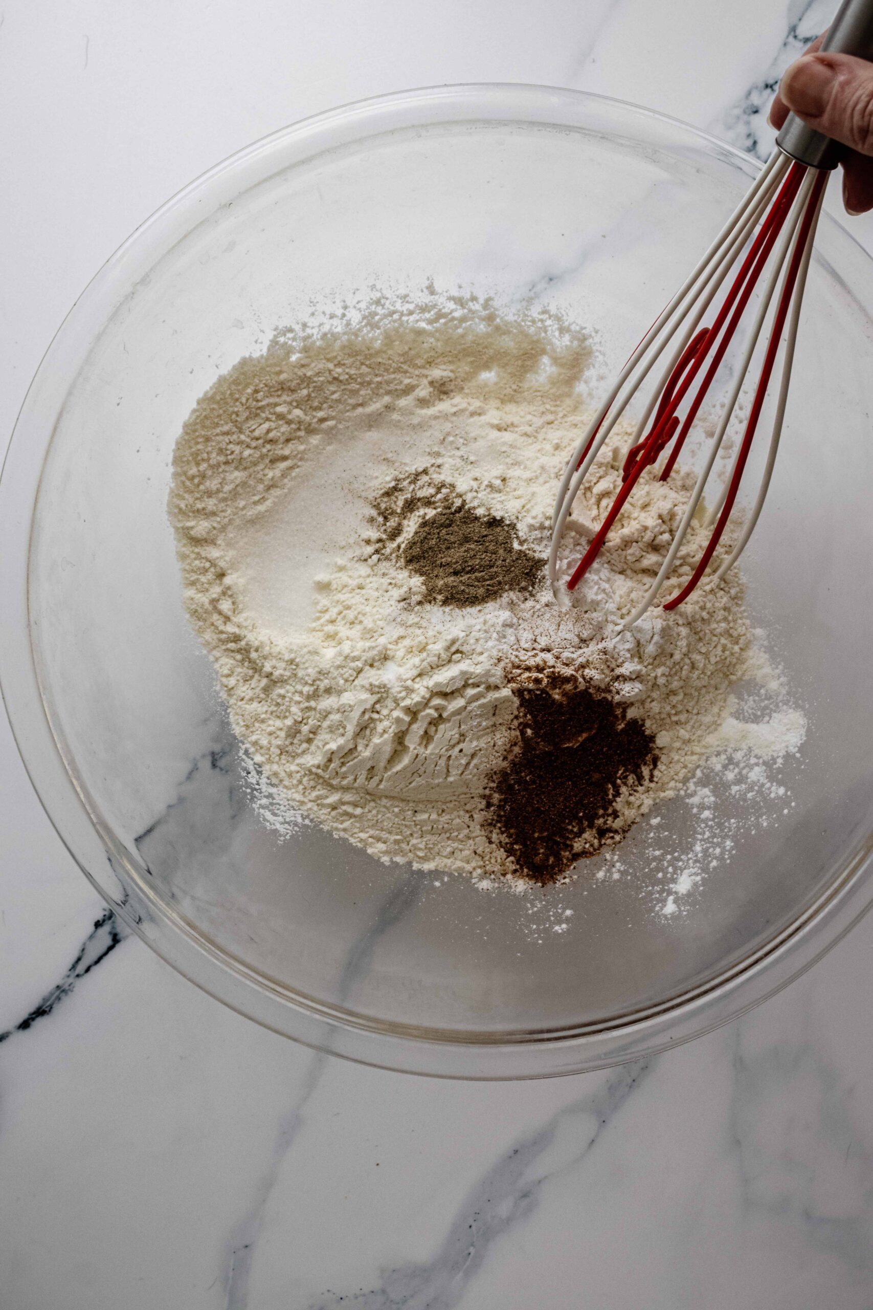 Dry ingredients in a glass bowl with a whisk
