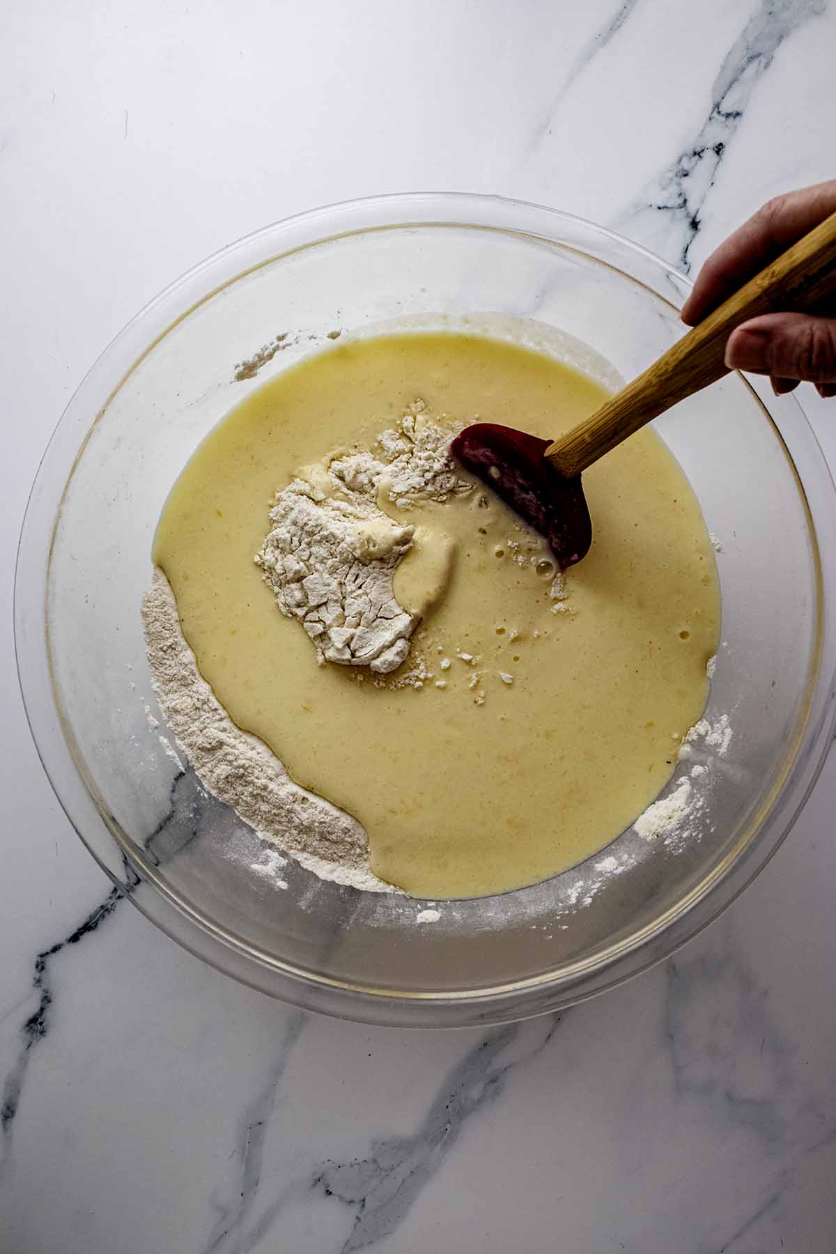 Wet and dry ingredients in a glass bowl with a whisk