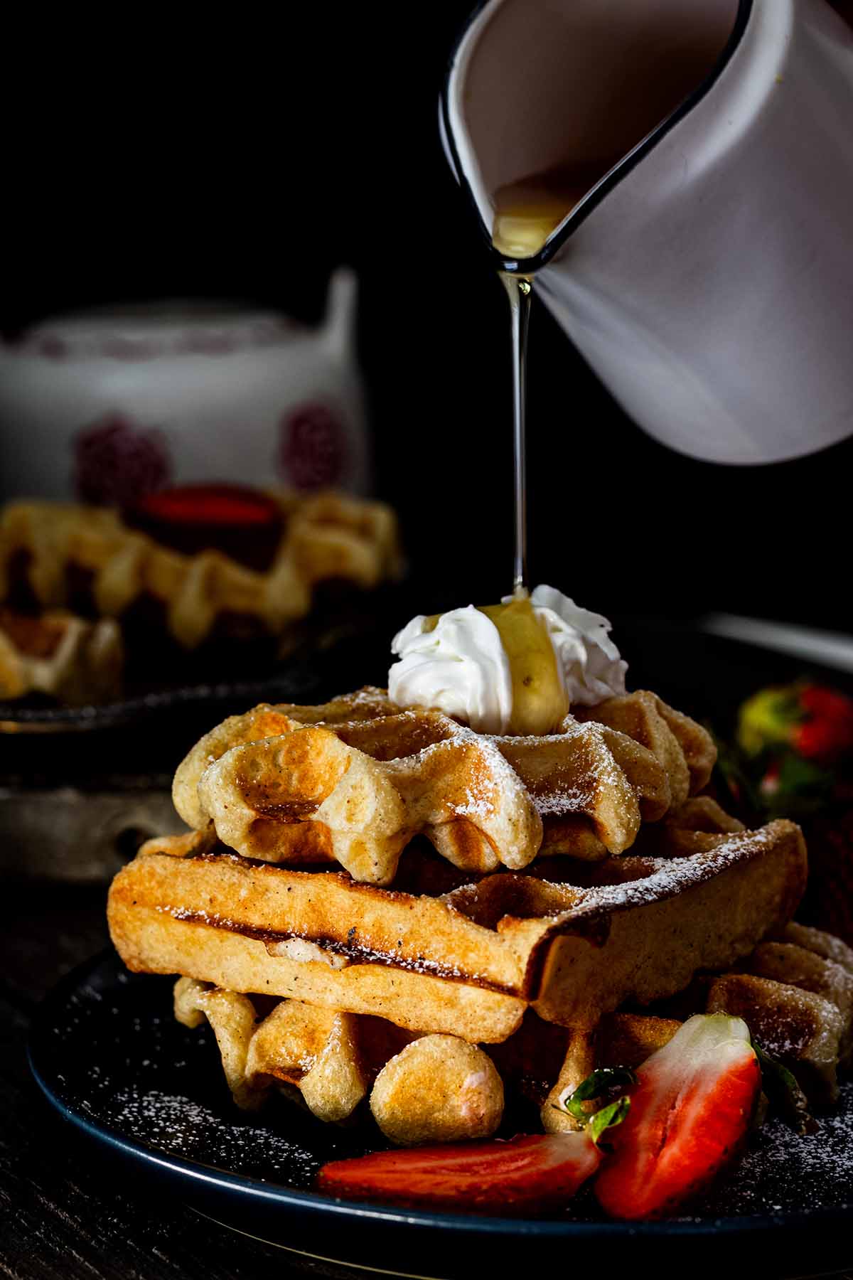 Syrup being poured onto a stack of buttermilk Belgian waffles