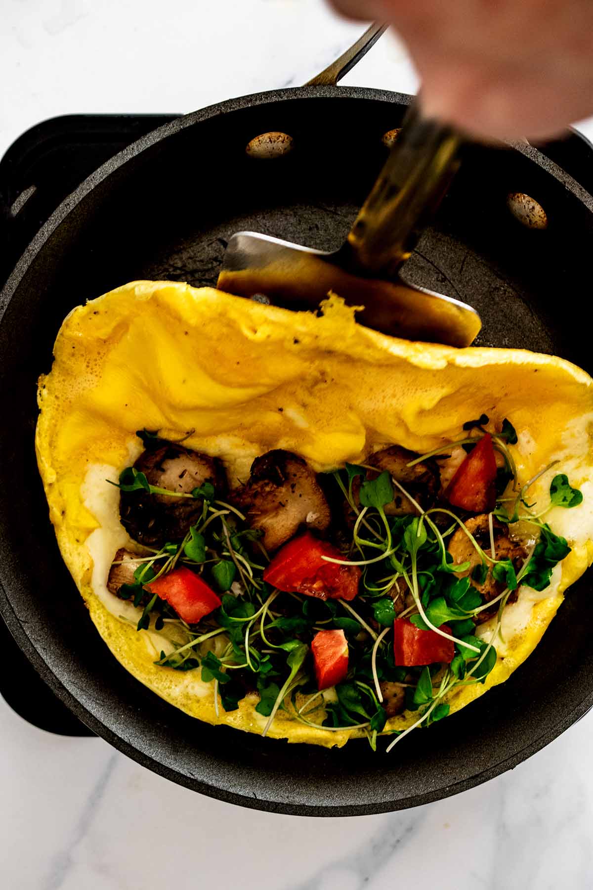 Spatula folding half of omelette over other filled half