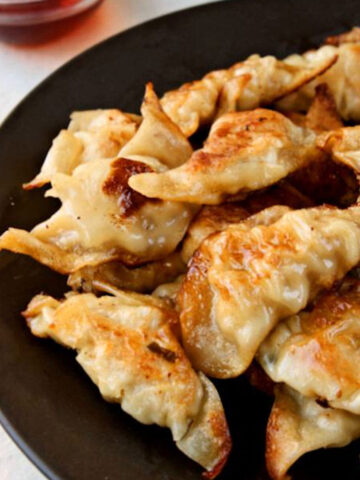 Close up of pork dumplings on a black platter.
