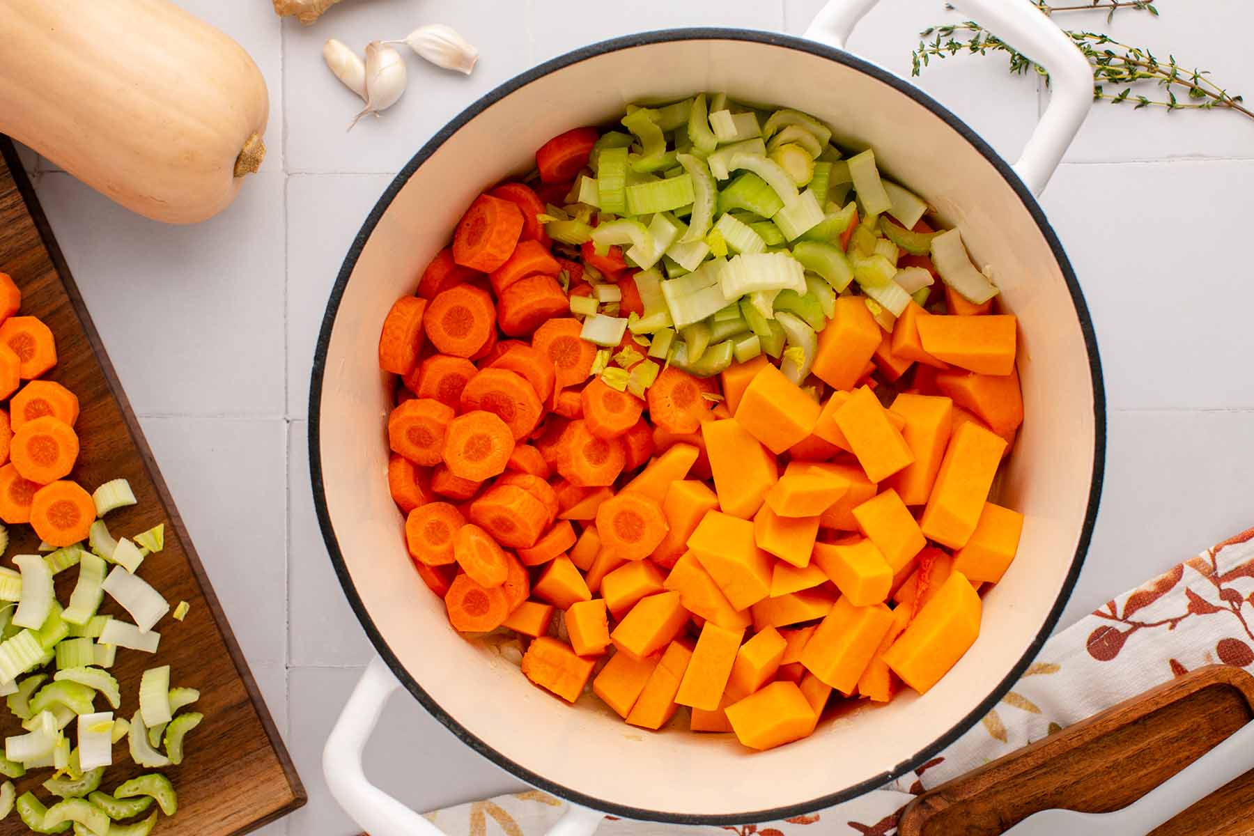 Butternut squash, sliced carrots, and sliced celery in Dutch oven with sauteed vegetables.