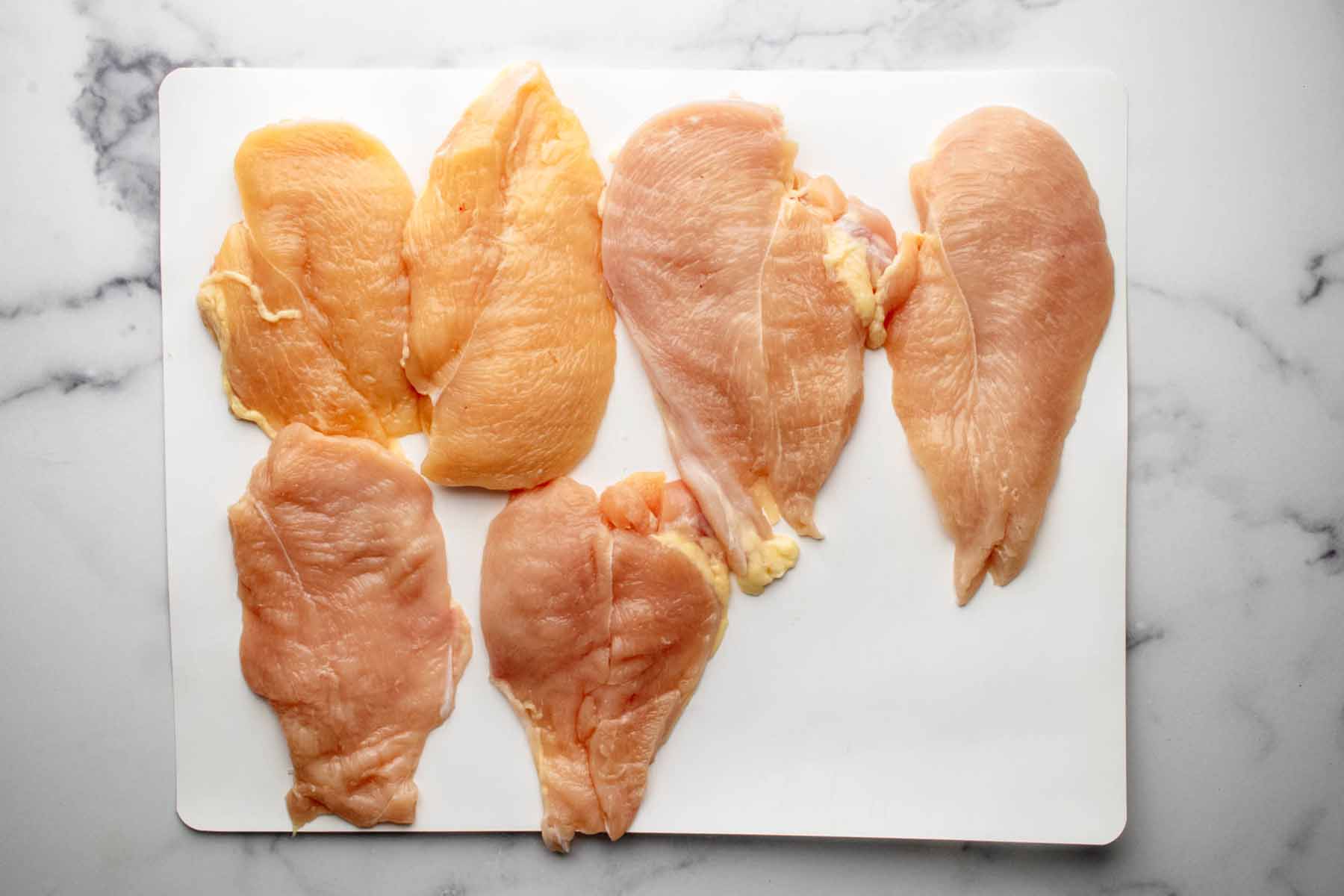 Three large chicken breasts split in half lengthwise to make six chicken cutlets.
