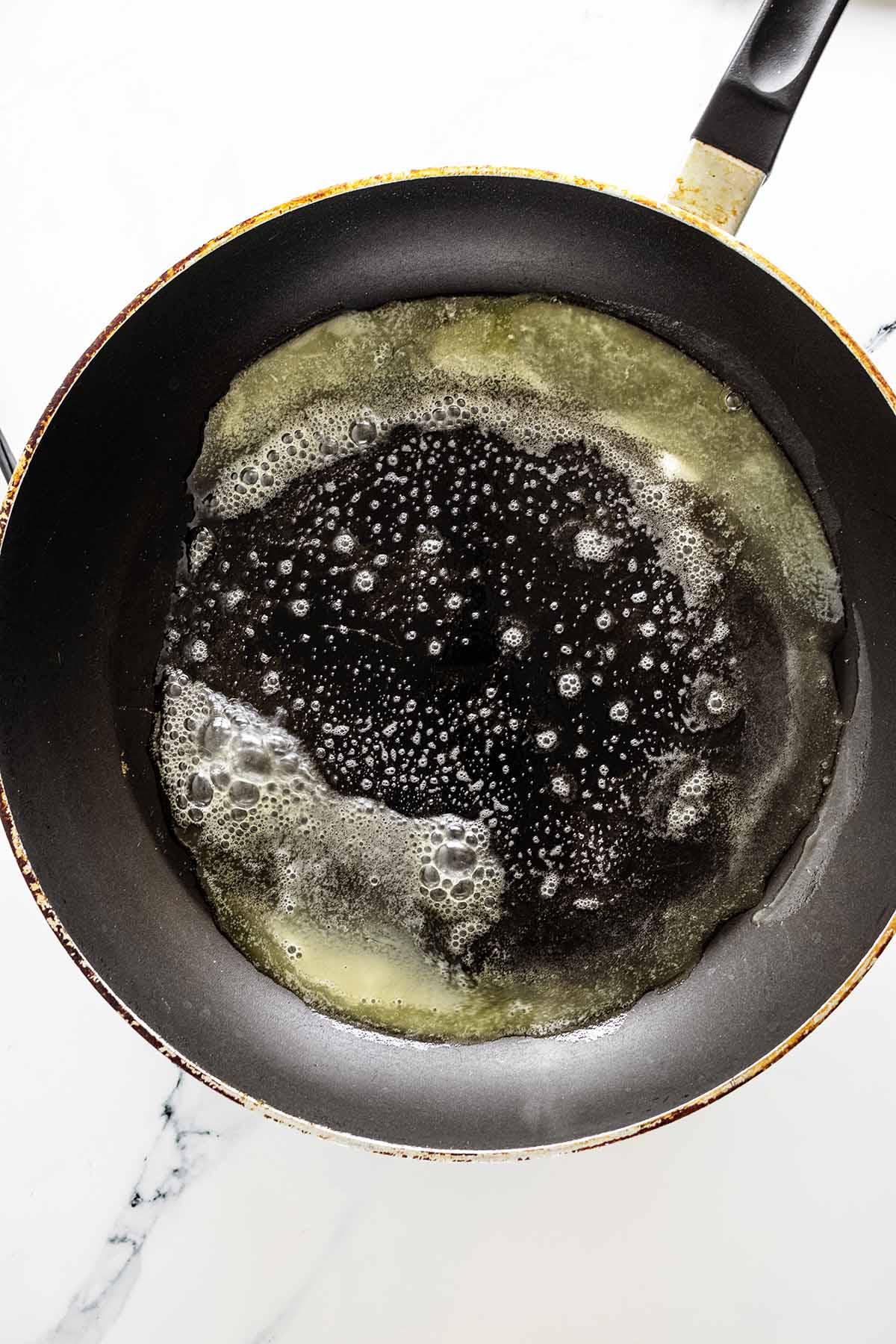 Overhead view of melted butter in a skillet.