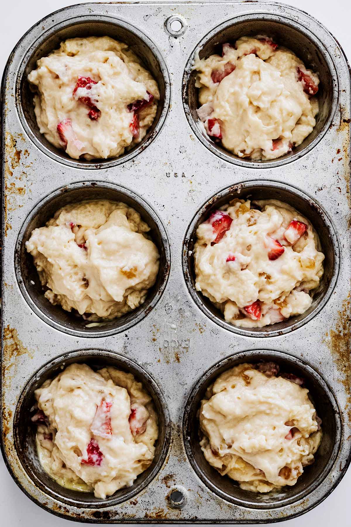Overhead view of strawberry muffin batter in a muffin tin