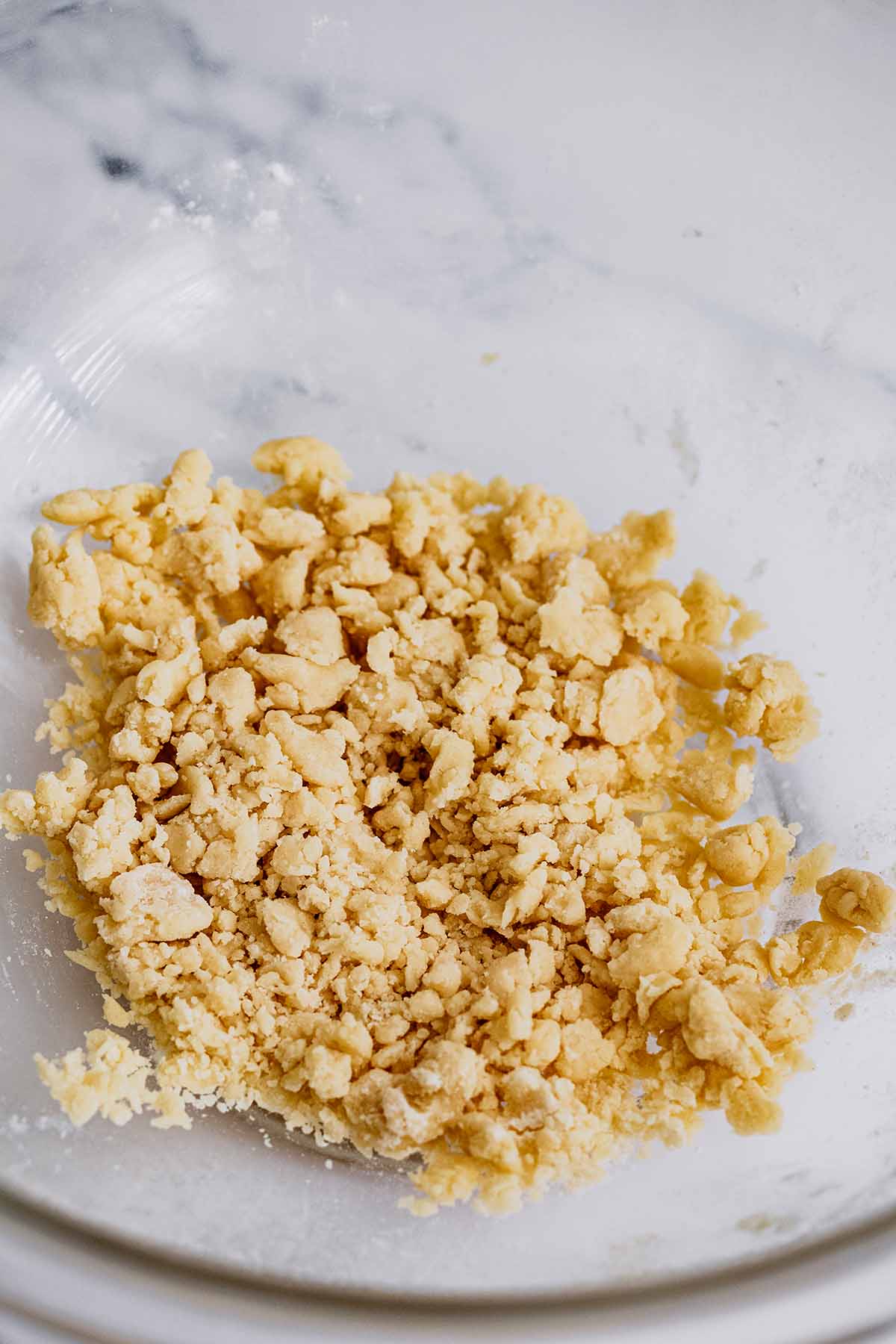 Flour and butter crumbles in a glass bowl