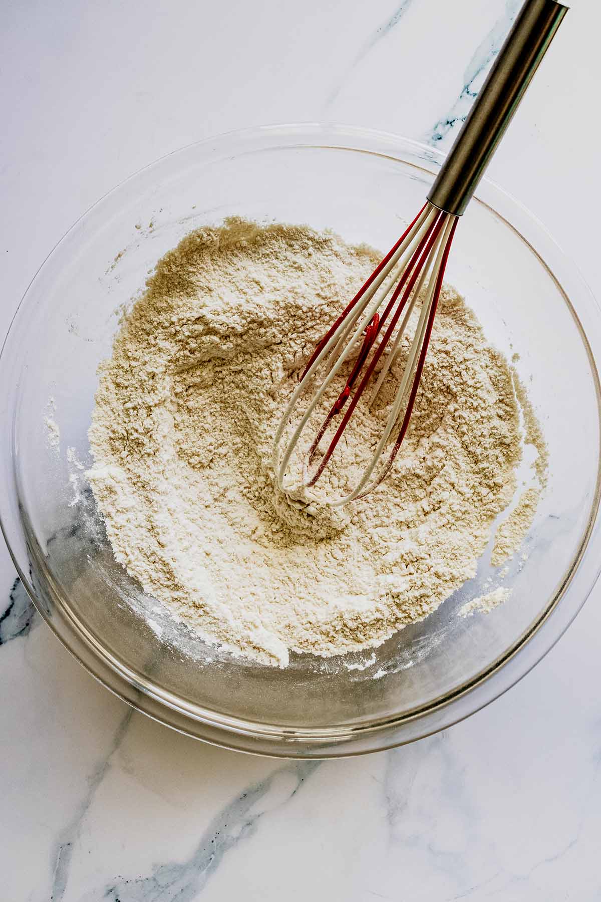 Dry ingredients in a glass bowl with a whisk