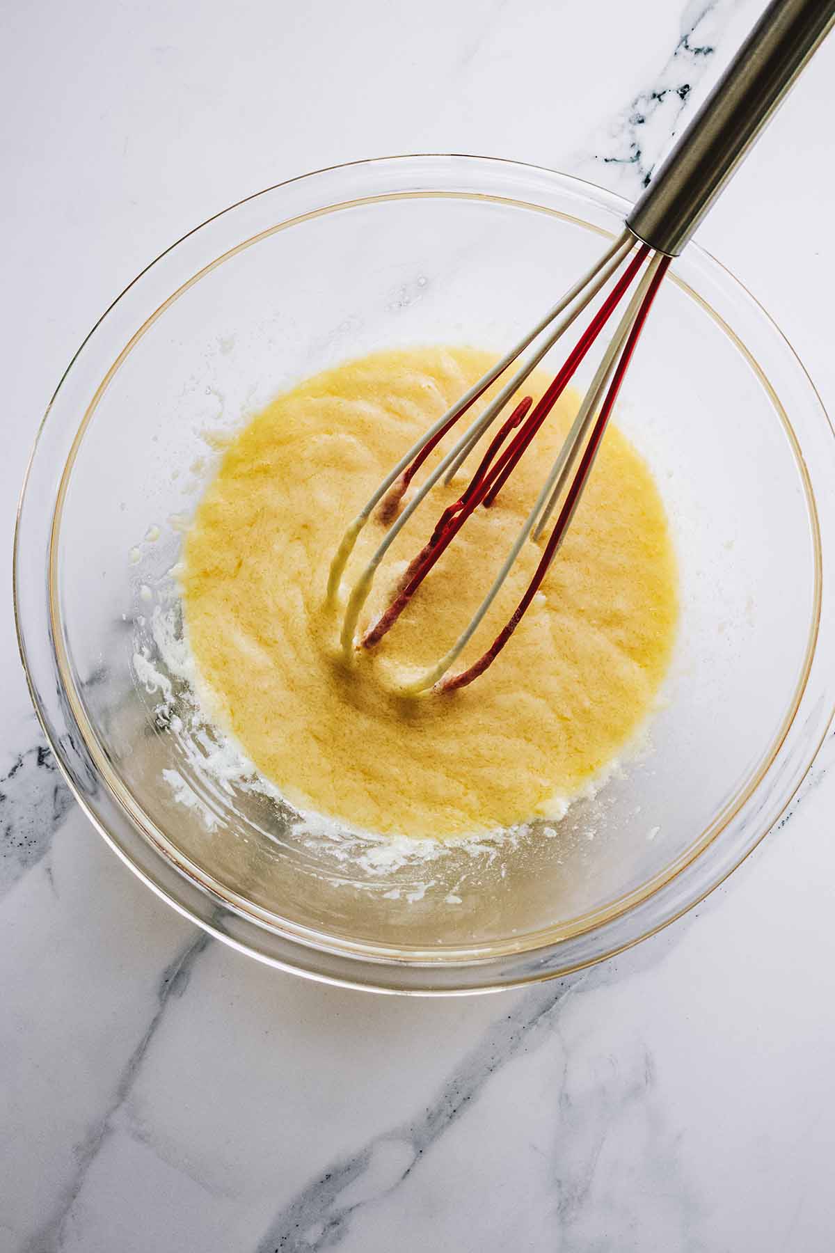 Wet ingredients in a glass bowl with a whisk