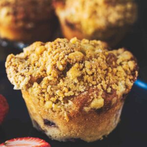 Strawberry muffins on a blue plate with sliced strawberries