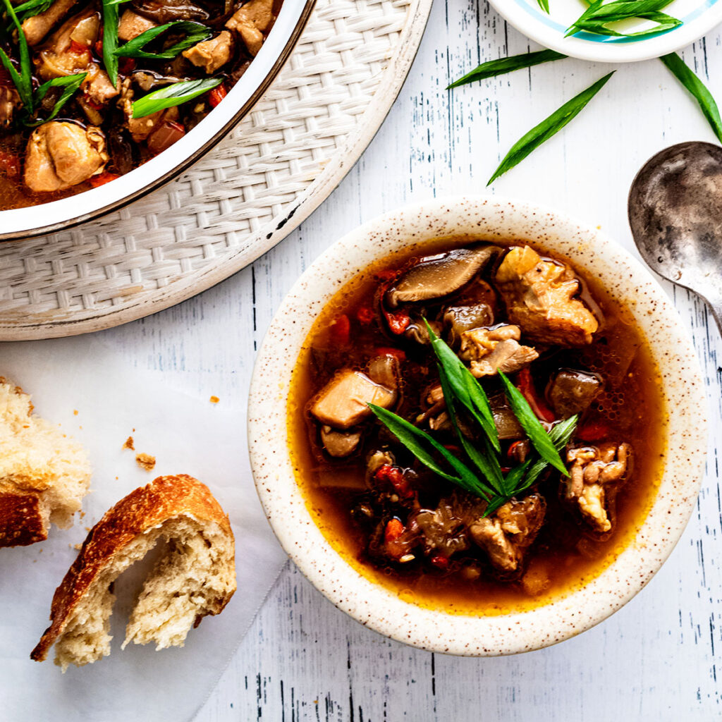 Overhead view of chicken soup in a white bowl with green onions