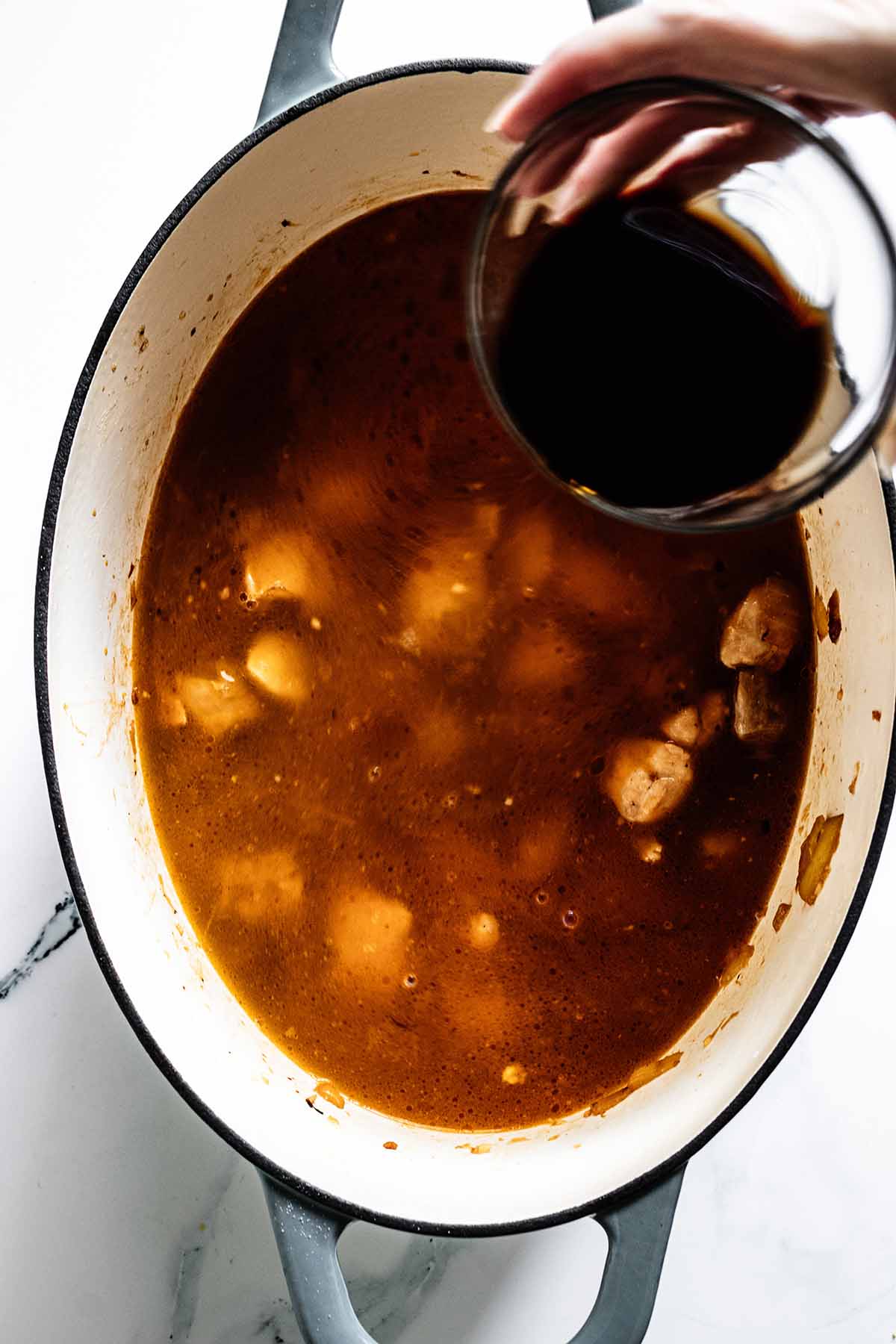 Overhead view of soy sauce being added to pot of soup