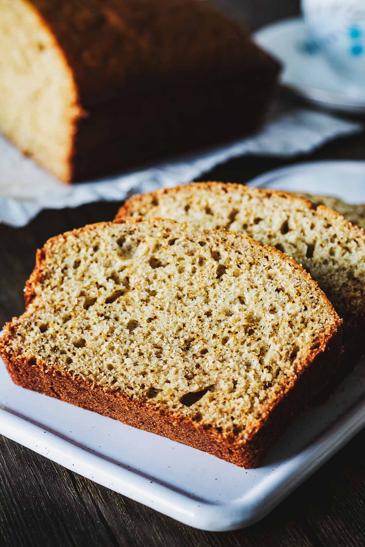Two slices of cardamom quick bread on a white platter