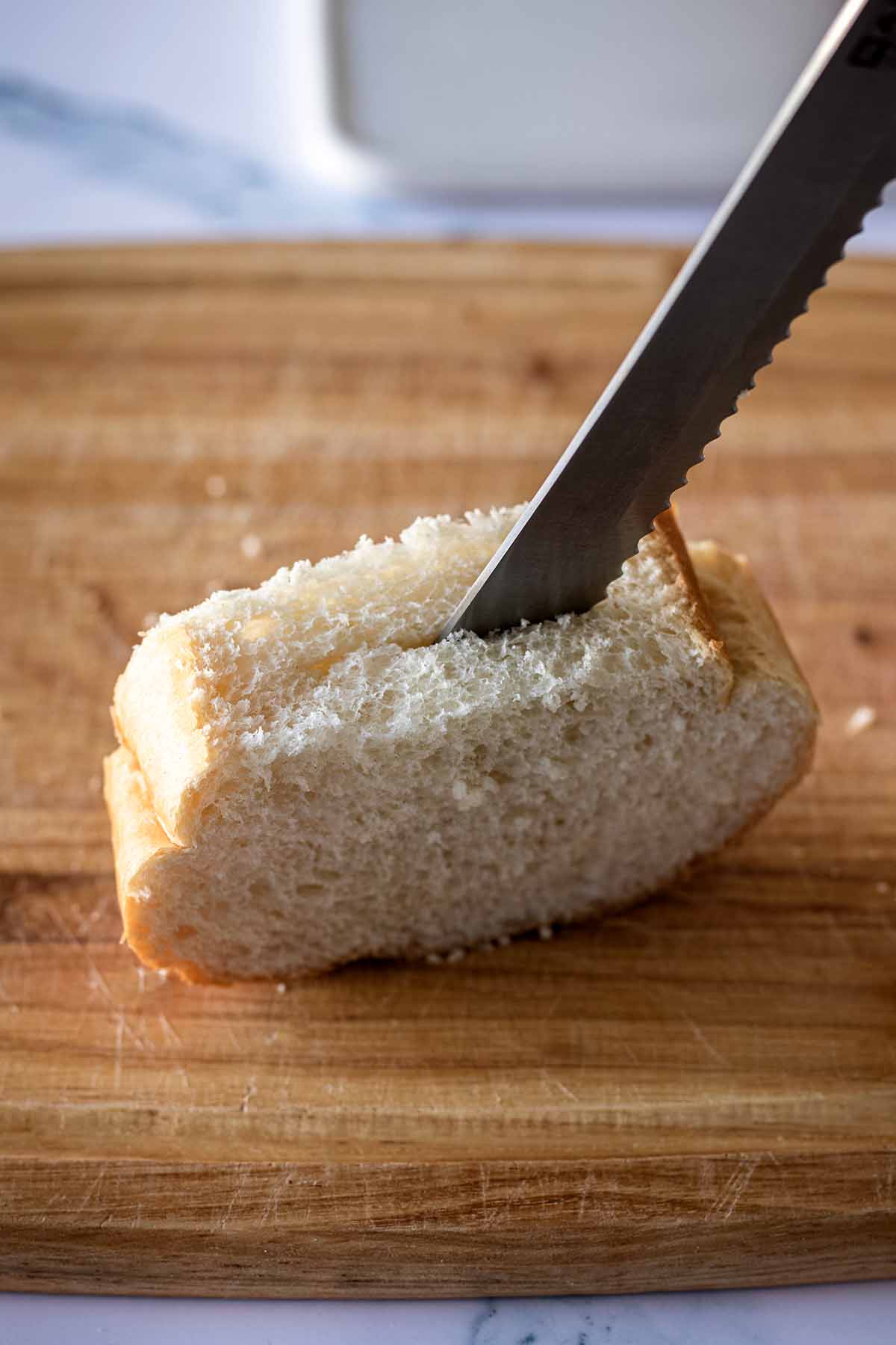 Knife cutting a slit in a slice of bread on a cutting board