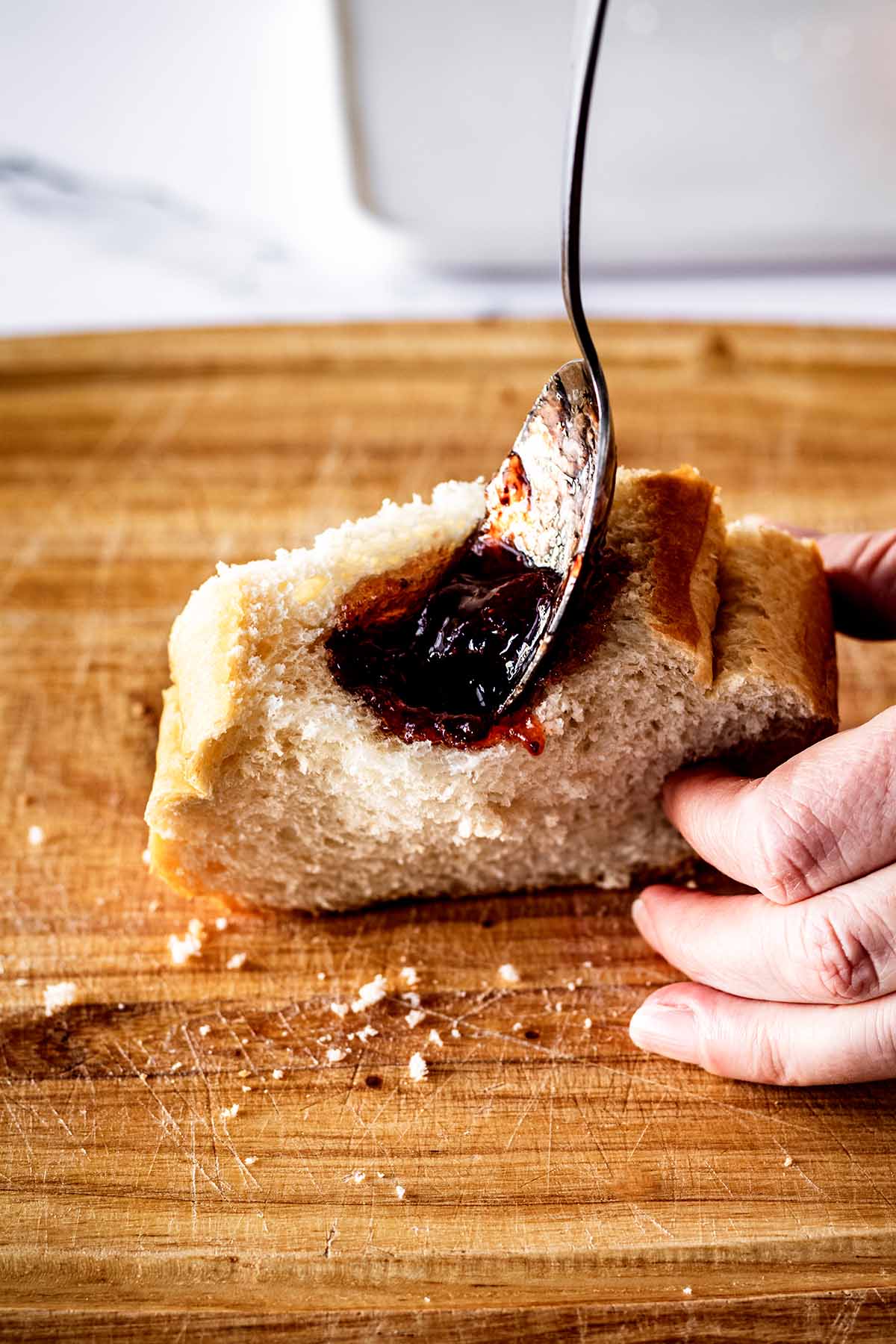 Spoon filling pocket in slice of bread with strawberry preserves