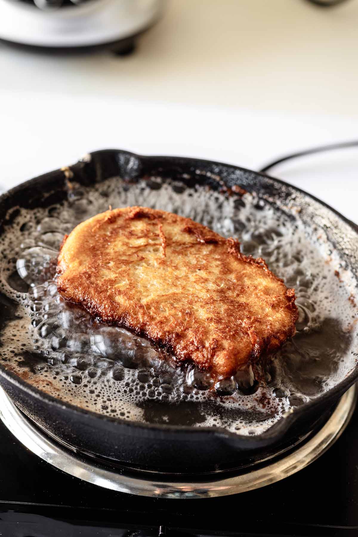Stuffed French toast cooking in hot oil in a cast iron skillet