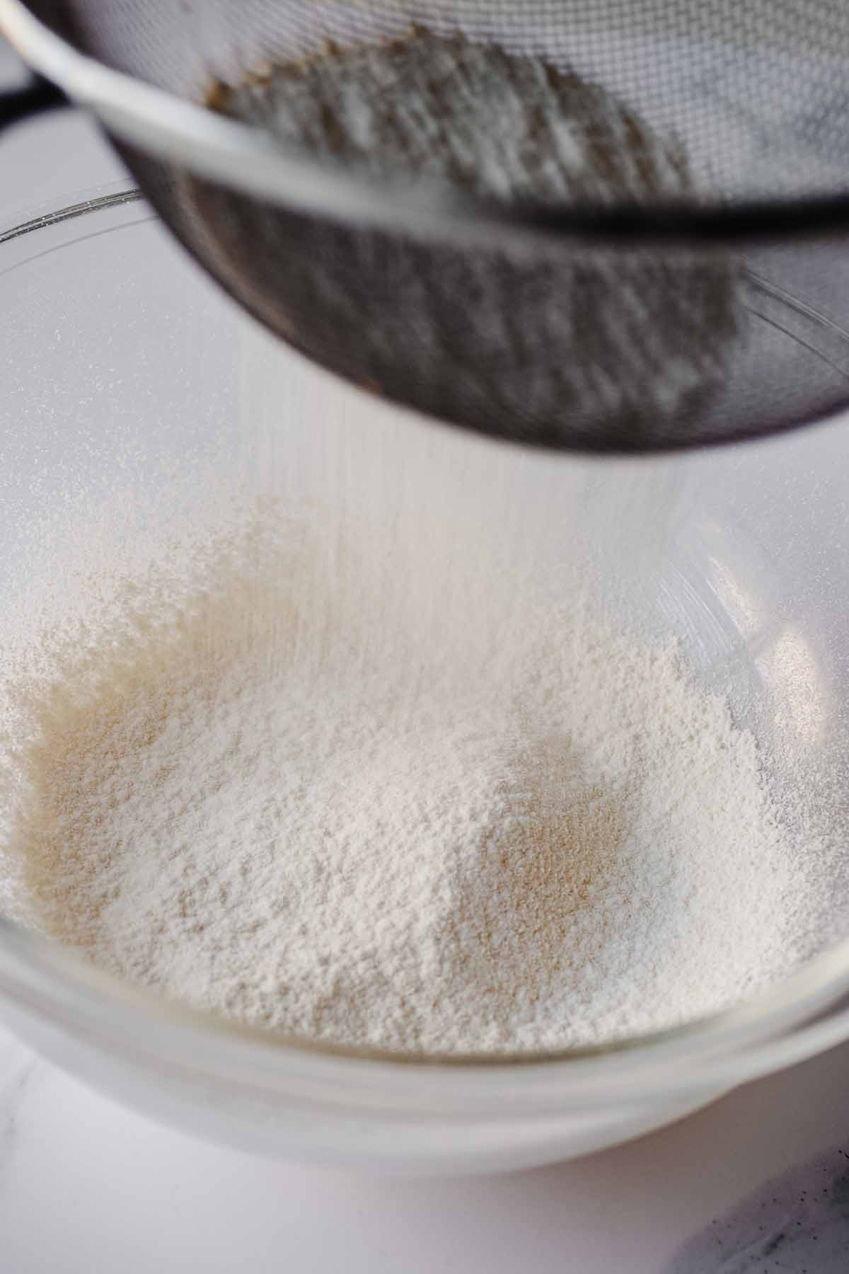 Flour being sifted into a glass bowl