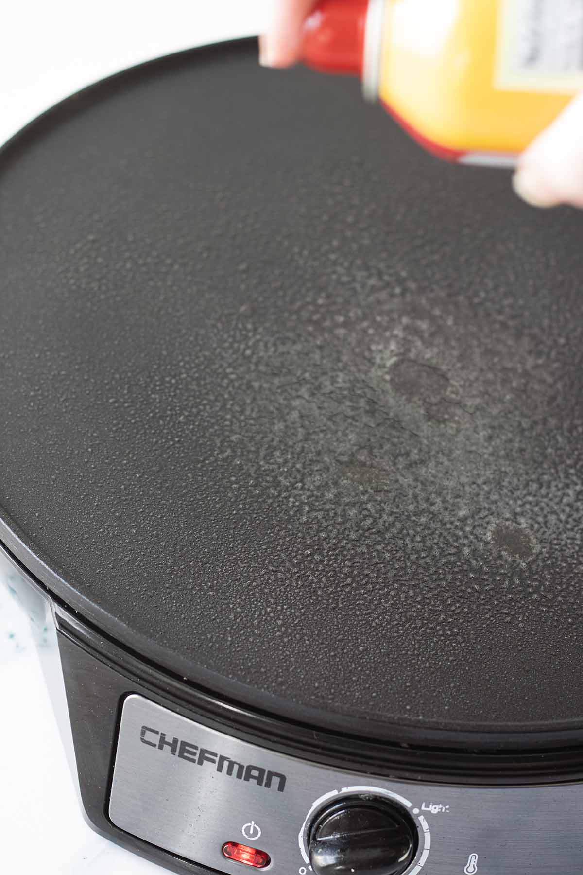 Spraying cooking spray on an electric griddle