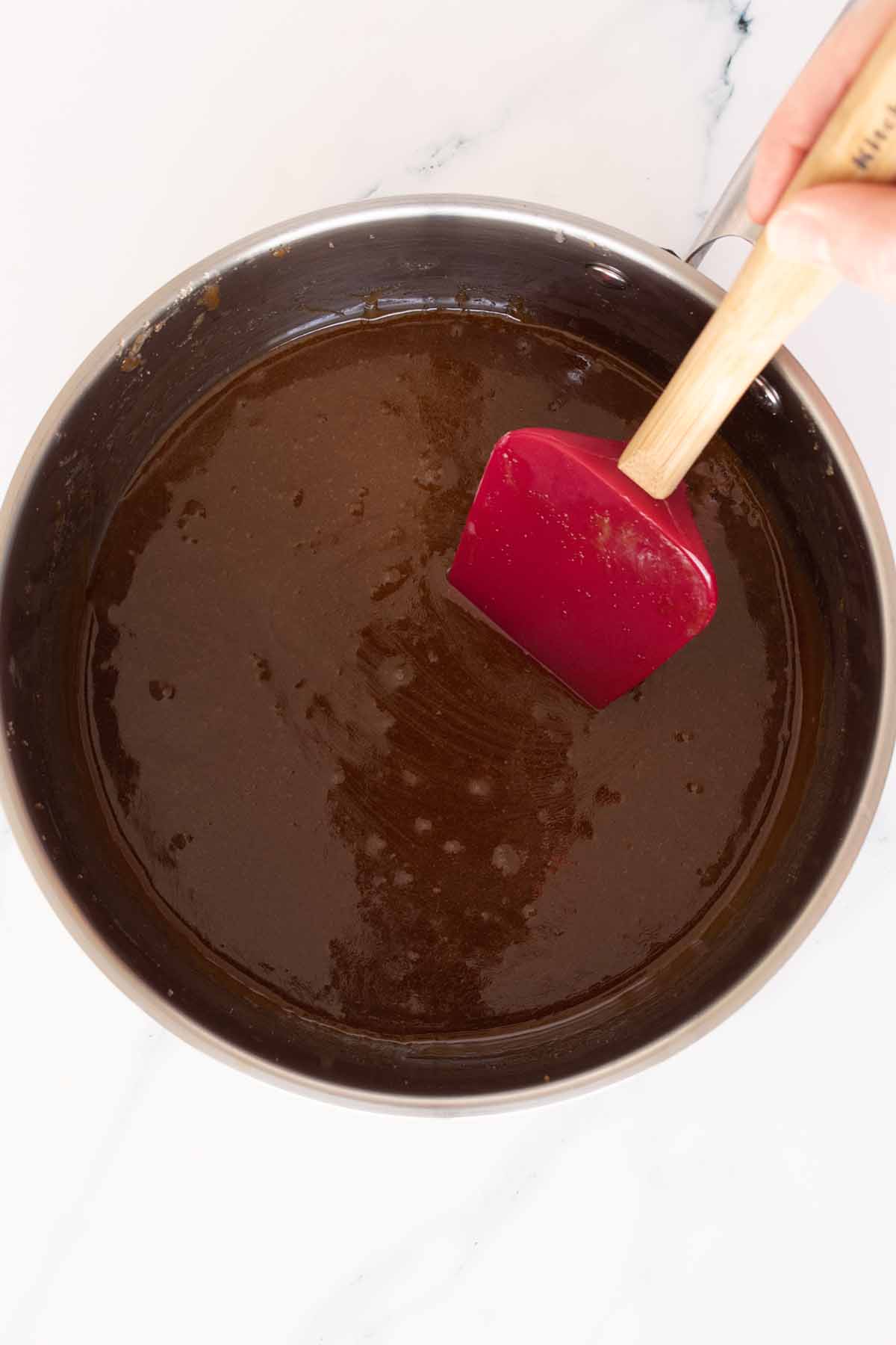 Cooked butter and sugar mixture in a saucepan with a red spatula