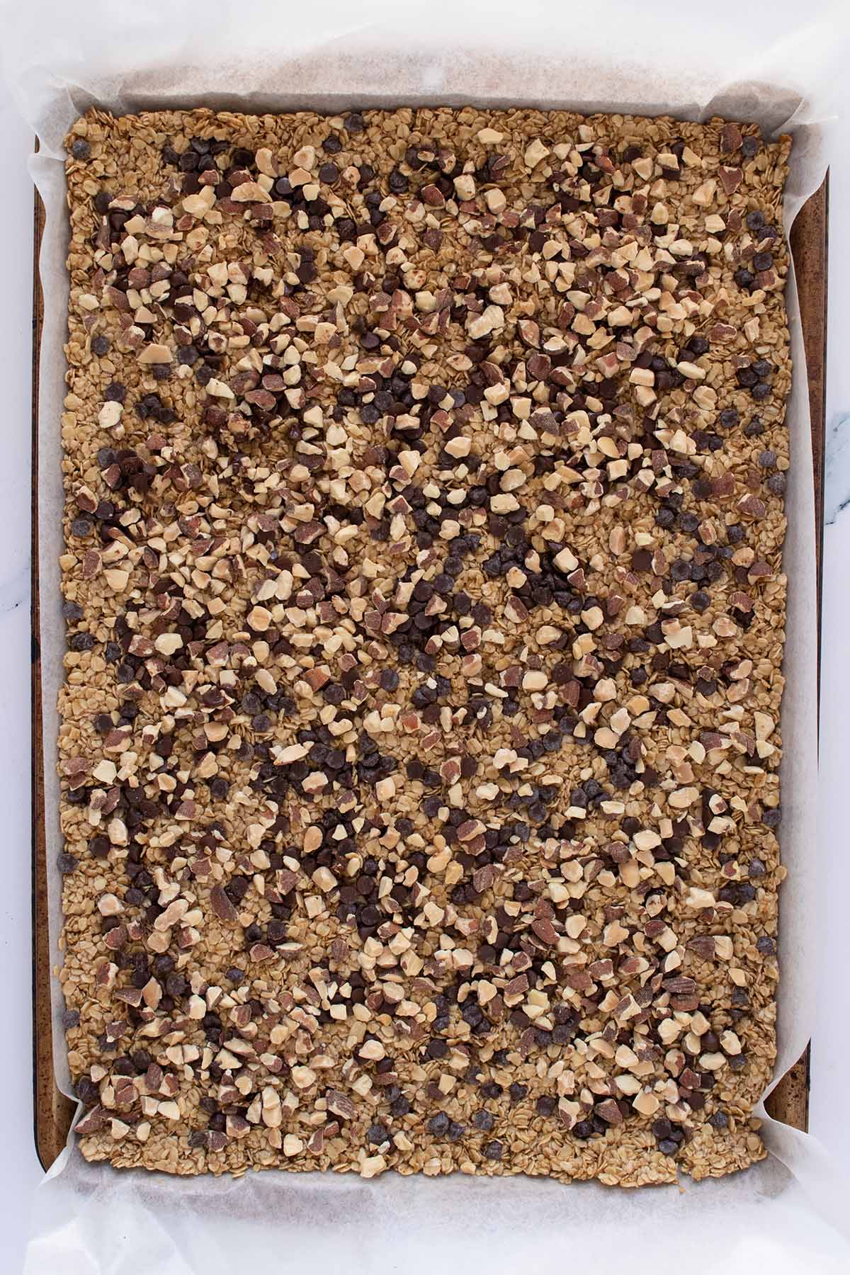 Overhead view of oat mixture sprinked with mini chocolate chips and toasted almonds