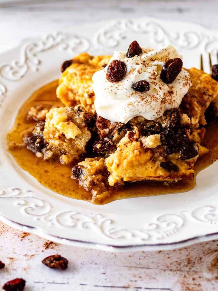 Close up of serving of raisin bread pudding on a white plate