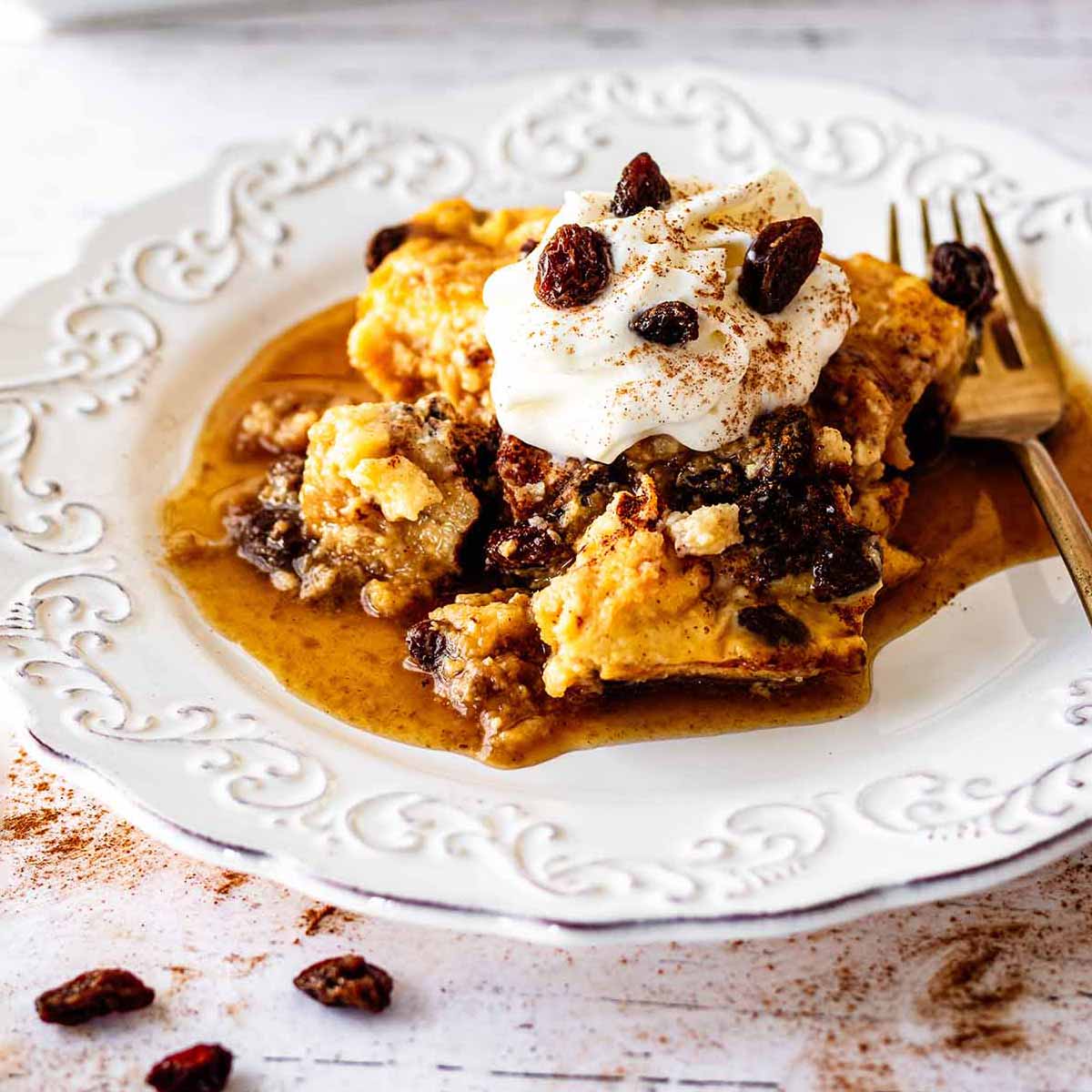 Close up of serving of raisin bread pudding on a white plate