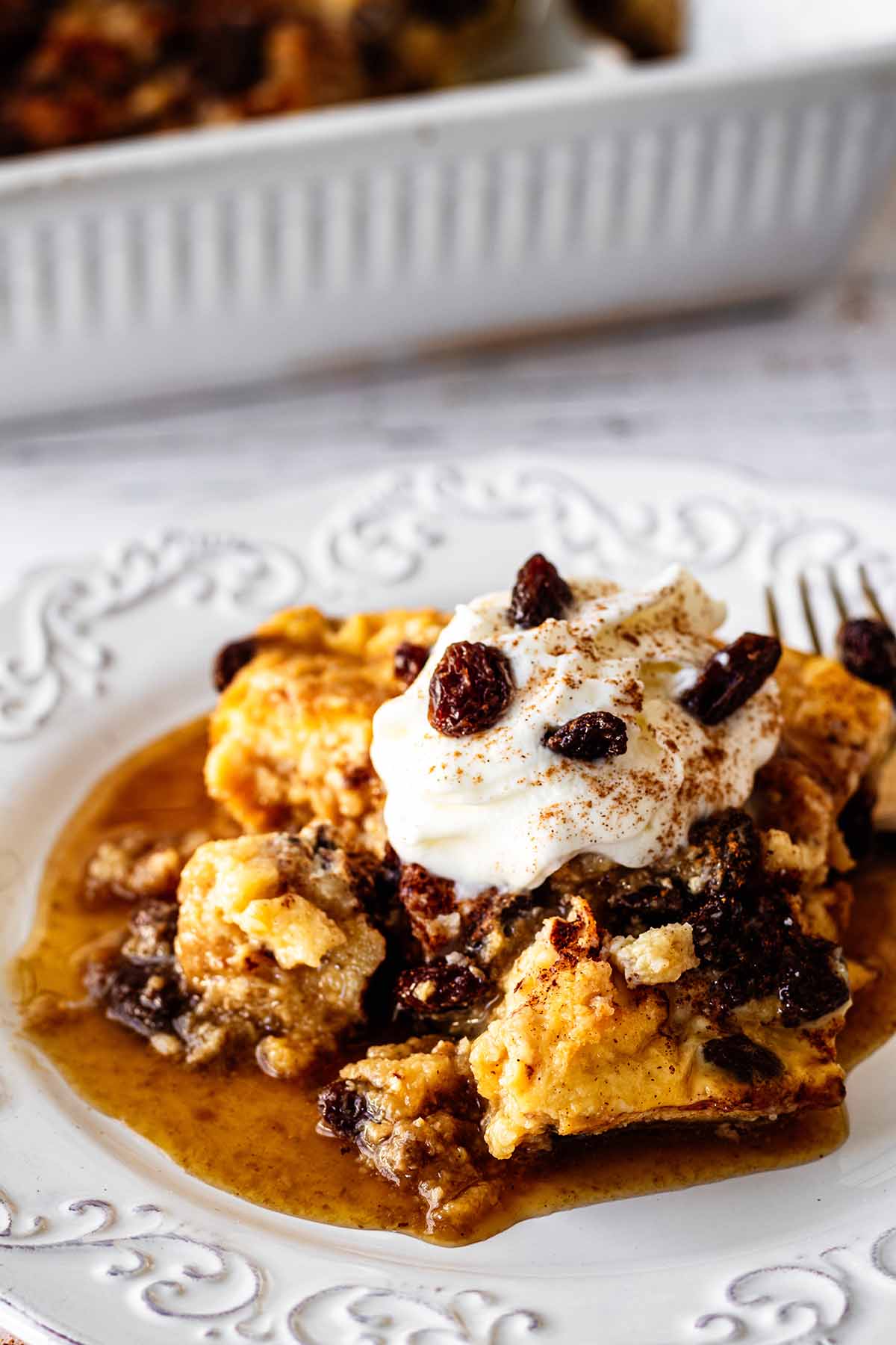 Close up of serving of raisin bread pudding on a white plate