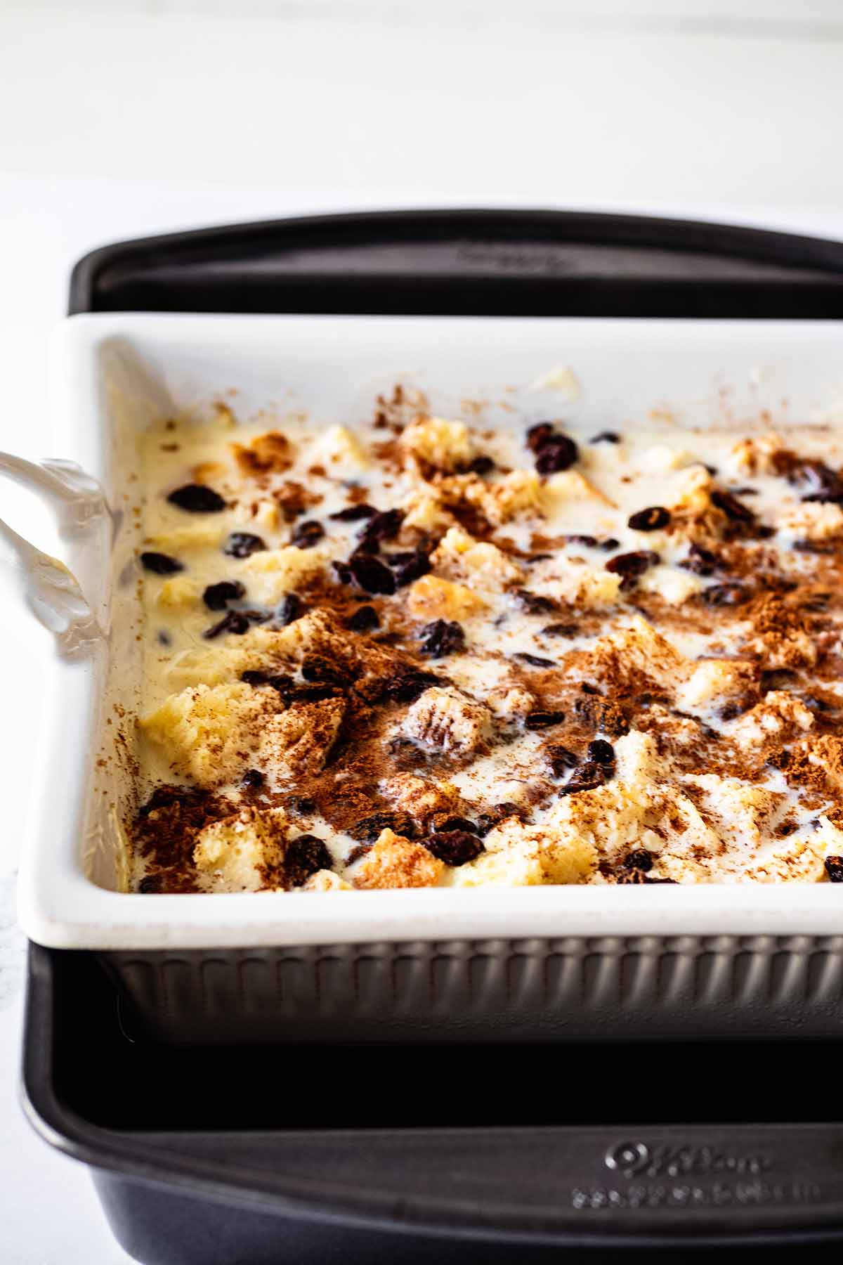 White baking dish containing all ingredients sitting inside of large metal baking dish