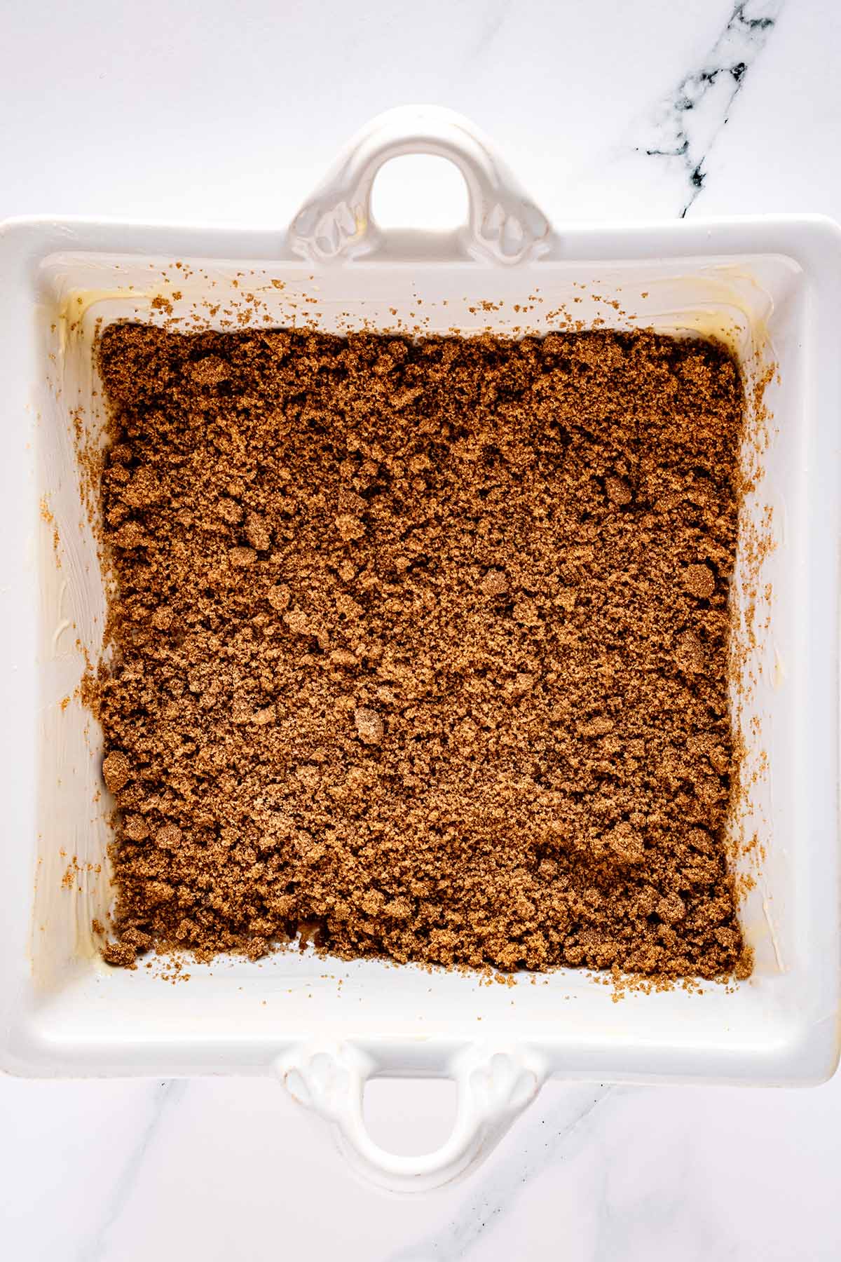 Brown sugar sprinkled on the bottom of a white baking dish