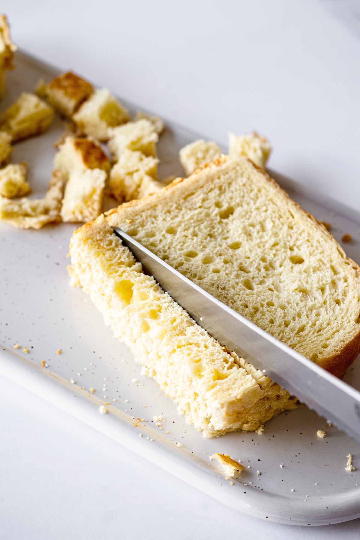 Buttered bread being diced on a white platter