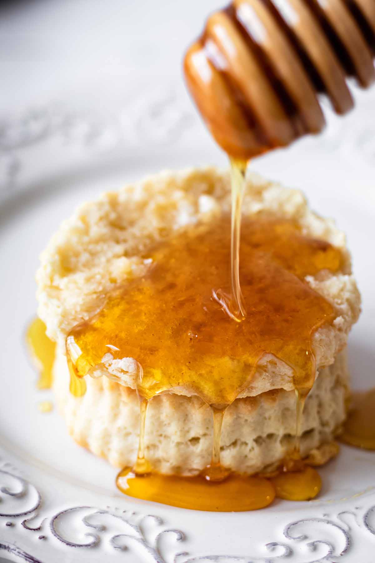 Close up of honey being drizzled on a sour cream biscuit