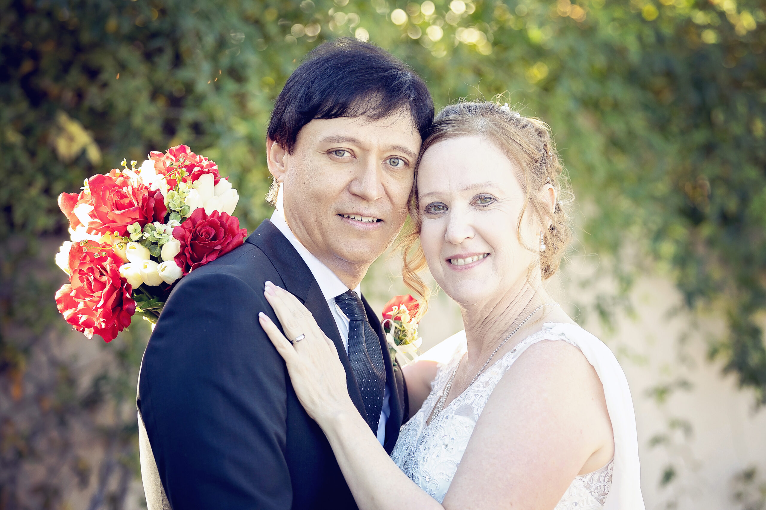 Groom and bride in front of a green hedge