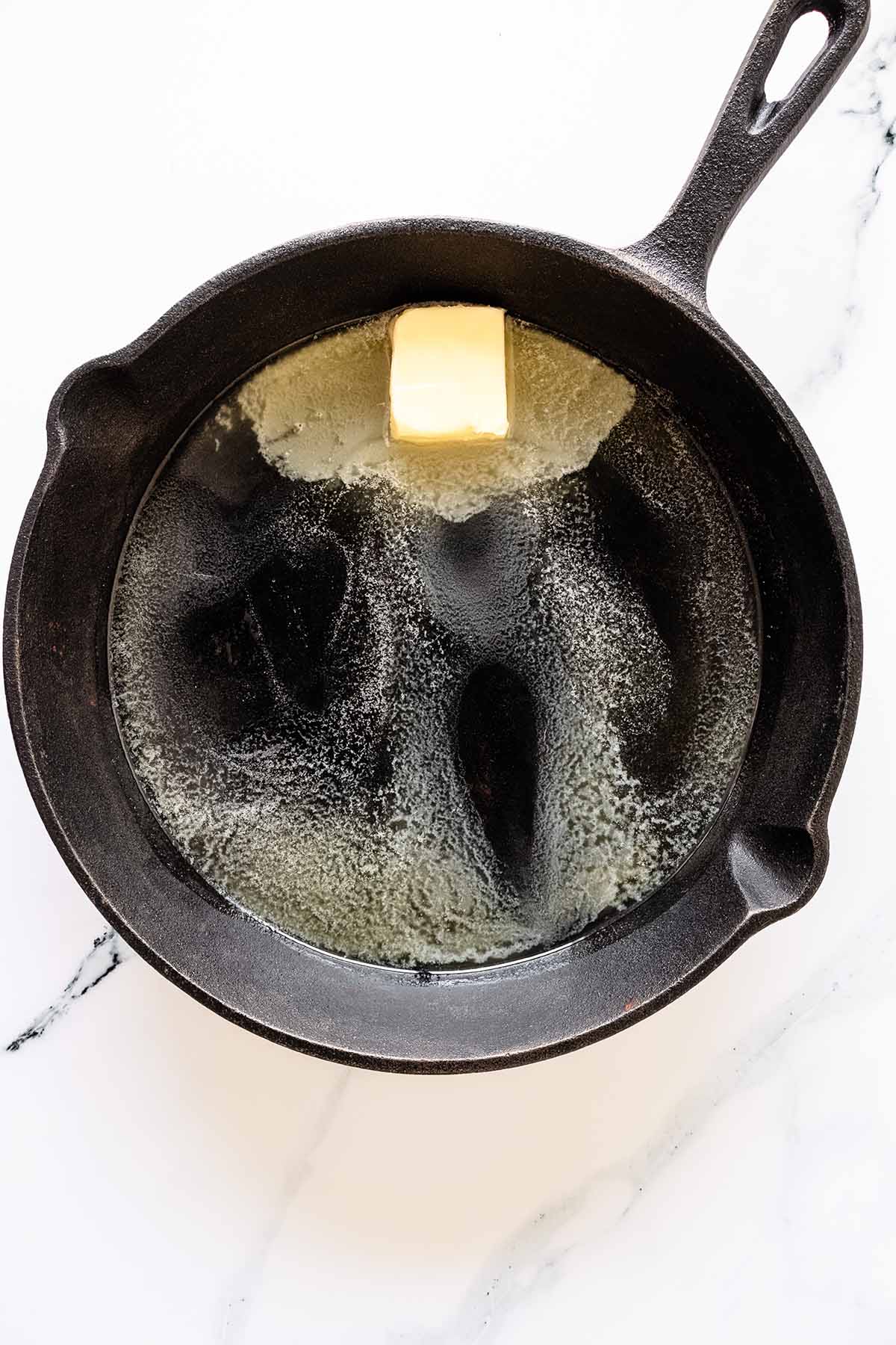 Overhead view of butter melting in a cast iron skillet