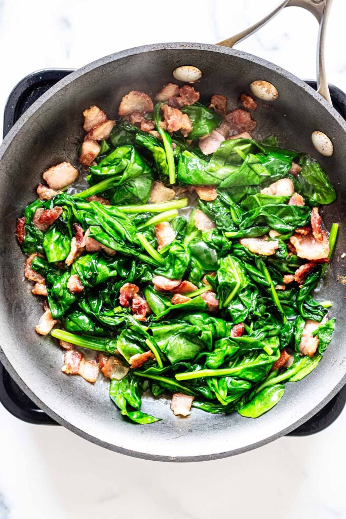 Bacon and spinach cooking in a skillet