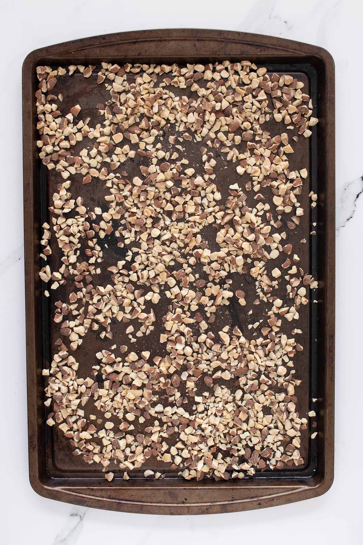 Overhead view of chopped almonds on a baking sheet