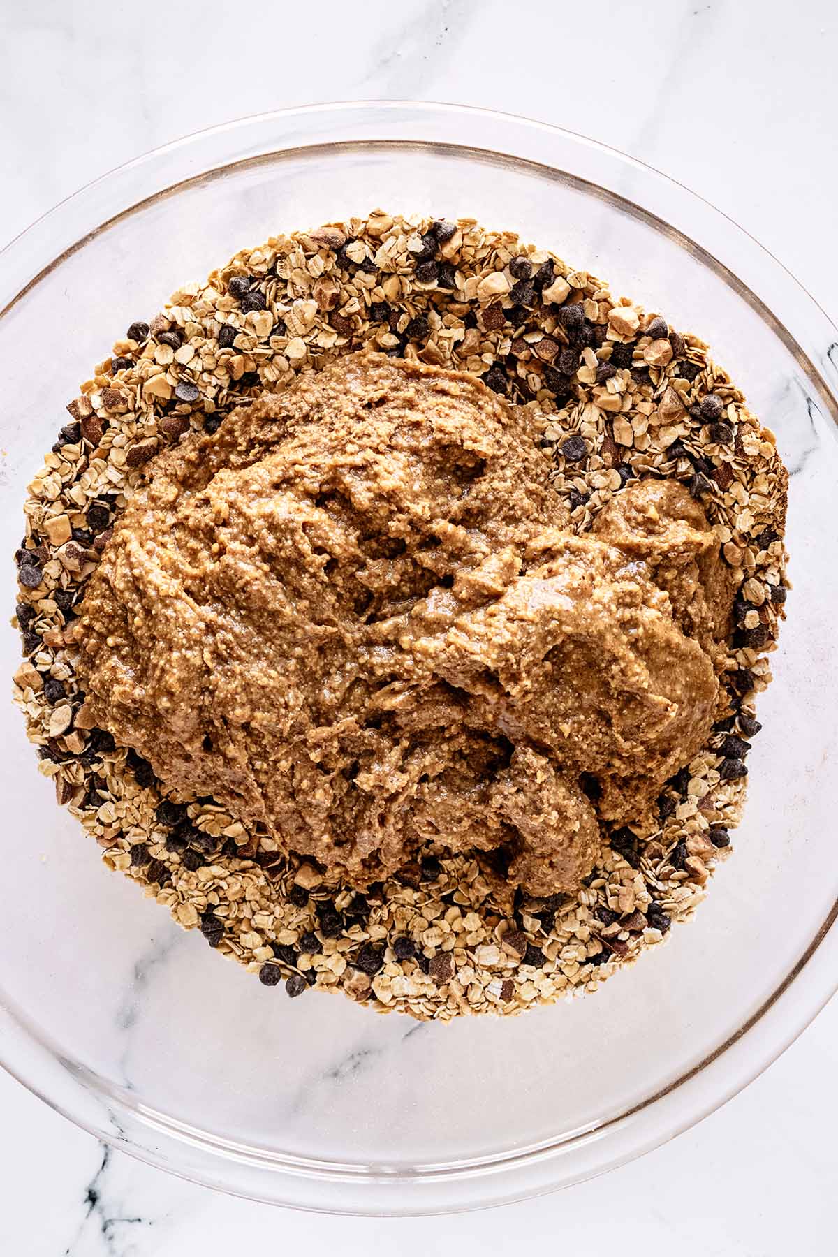 Peanut butter mixture in a glass bowl with oat mixture