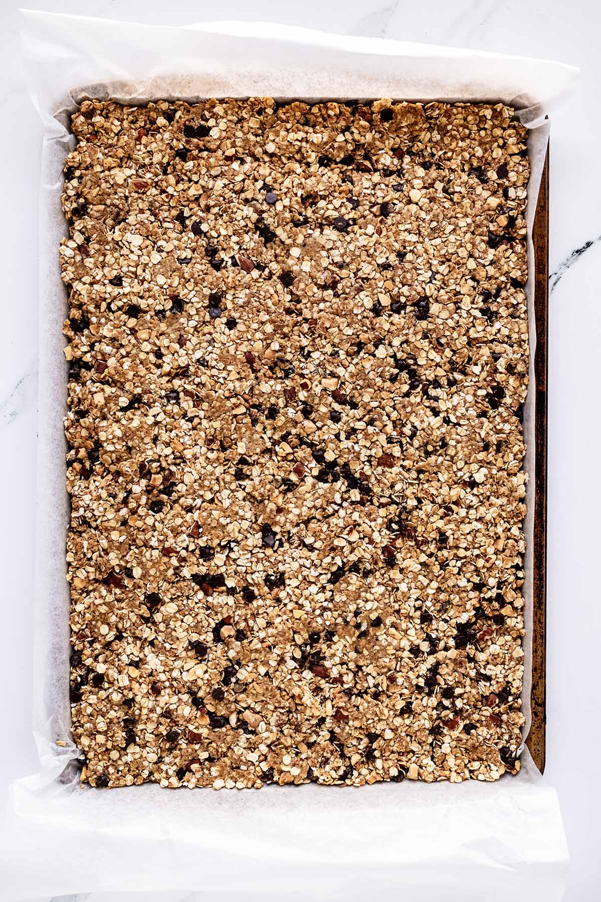 Overhead view of oatmeal bar mixture pressed into a baking sheet