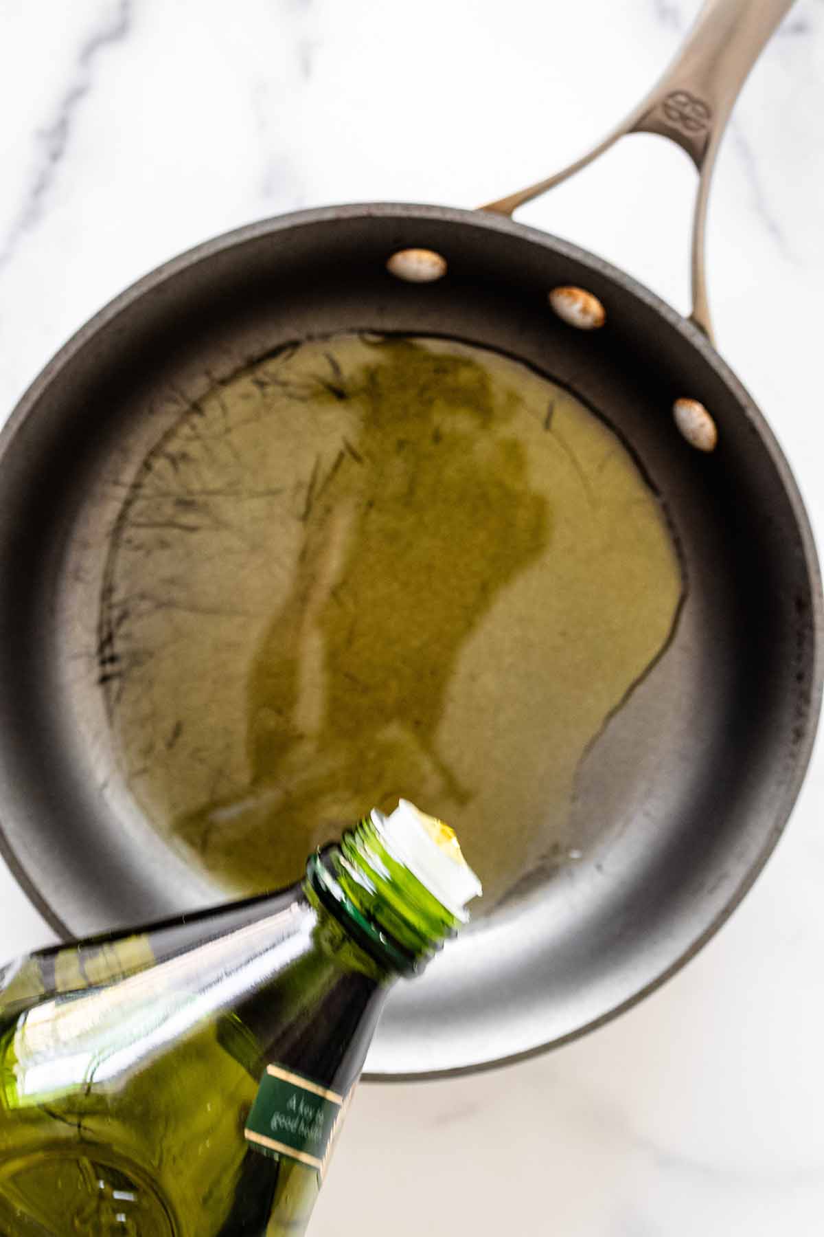 Overhead view of olive oil being poured into a skillet