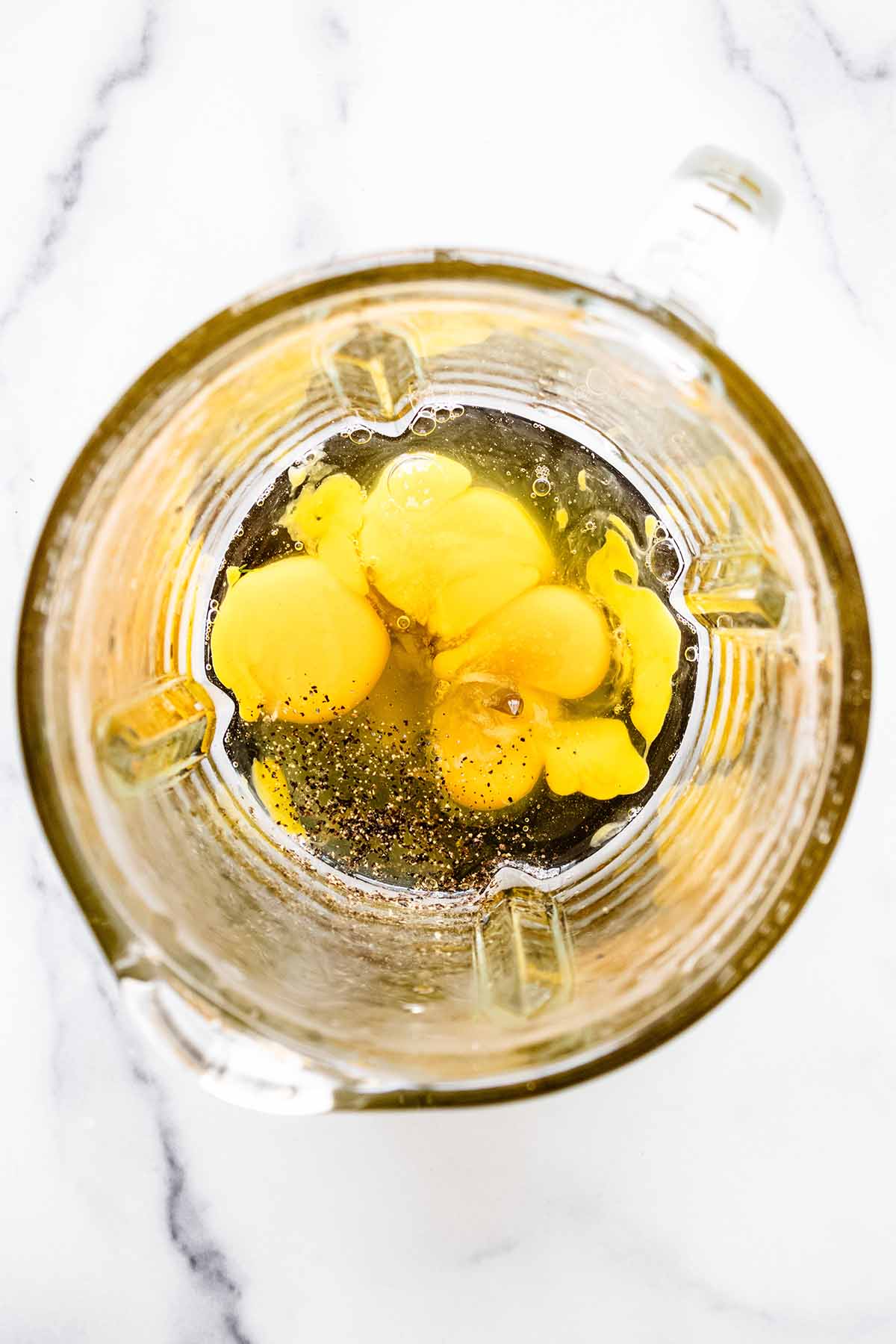 Overhead view of eggs and salt and pepper in a blender