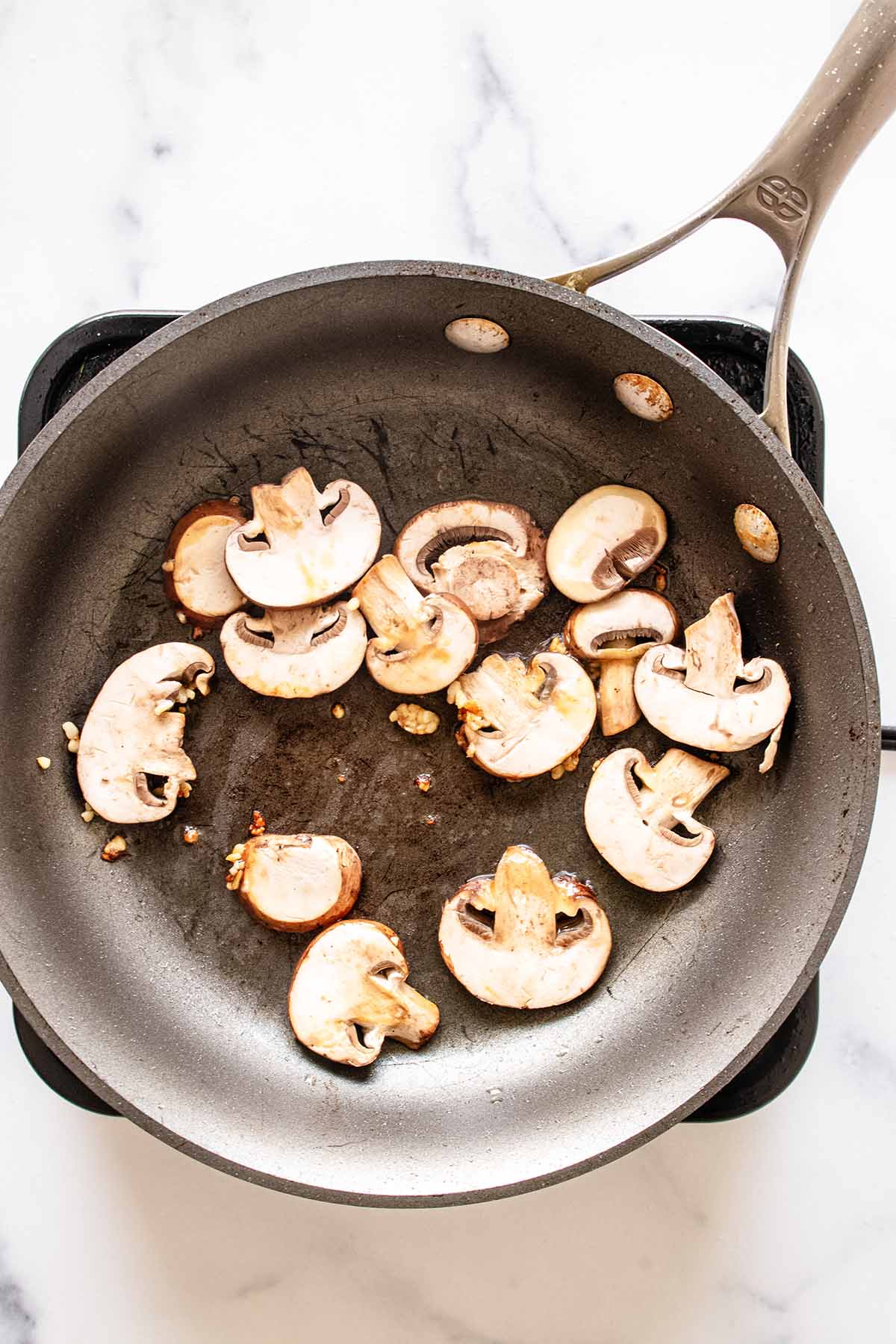 Sliced mushrooms and garlic cooking in a skillet