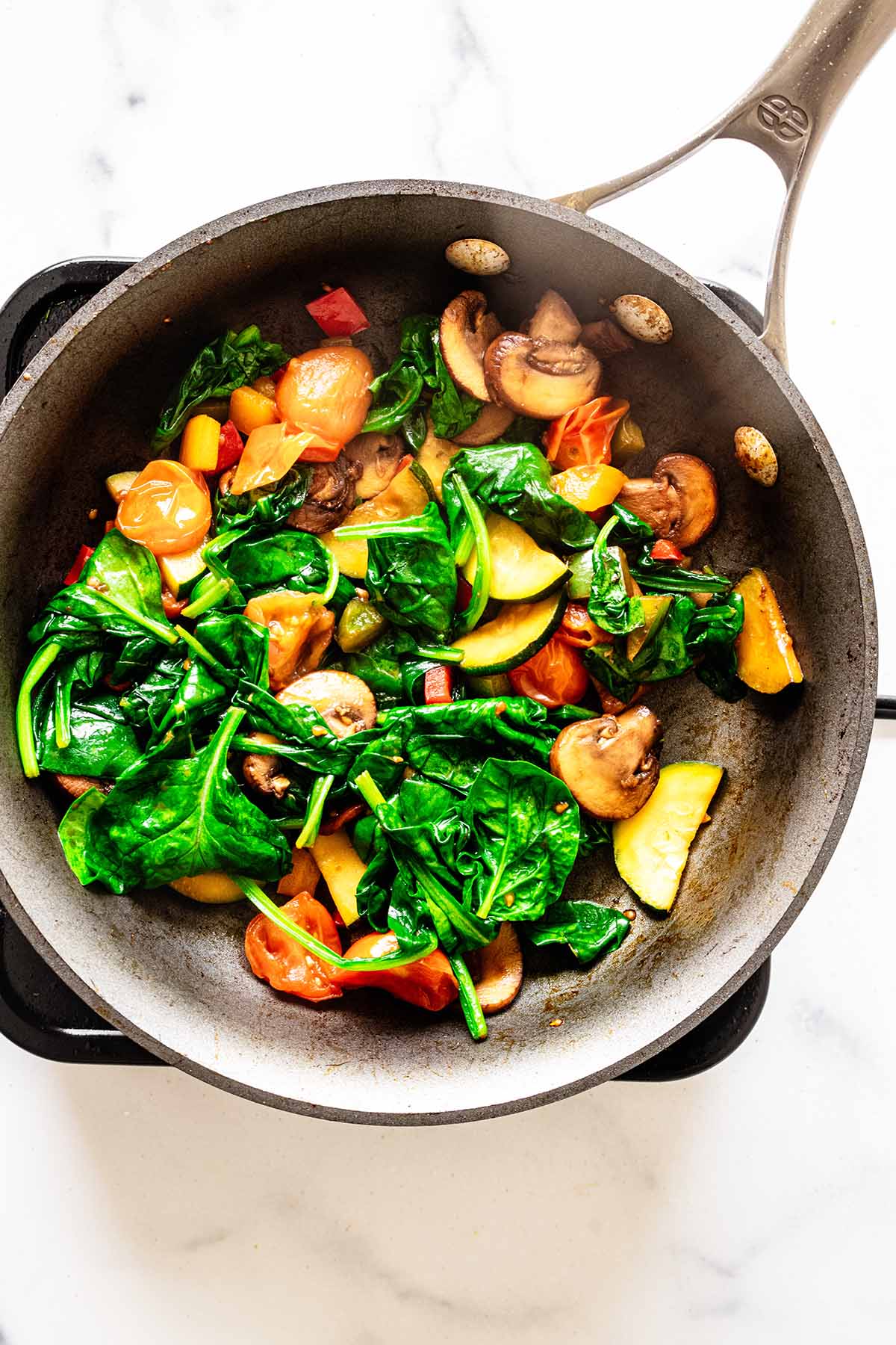 Cooked spinach and vegetables in a skillet