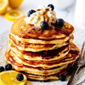 Stack of lemon blueberry pancakes on a white plate