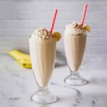 Two banana shakes in tall glasses with red and white straws