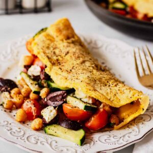 Front view of Greek omelette on a white plate with filling spilling out