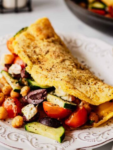 Front view of Greek omelette on a white plate with filling spilling out