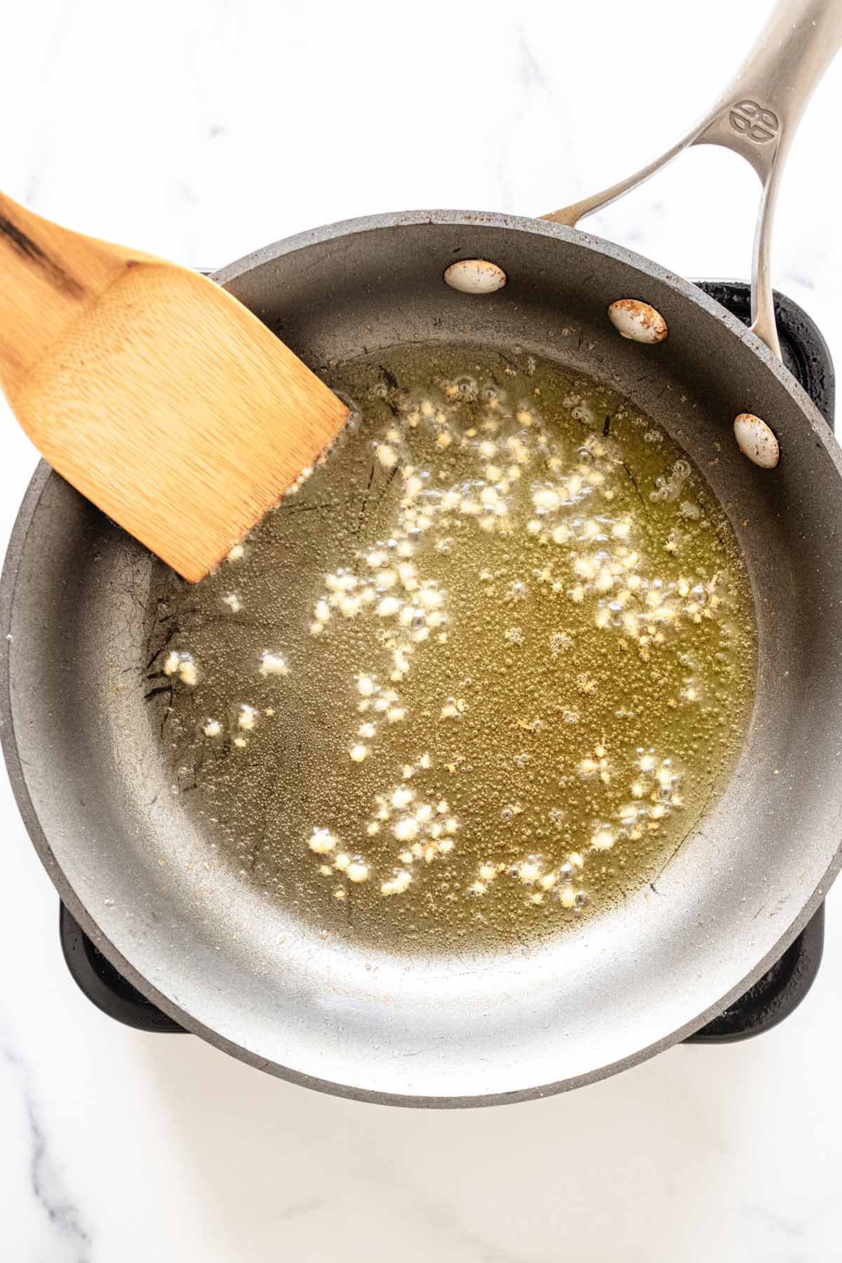 Overhead view of minced garlic cooking in a skillet
