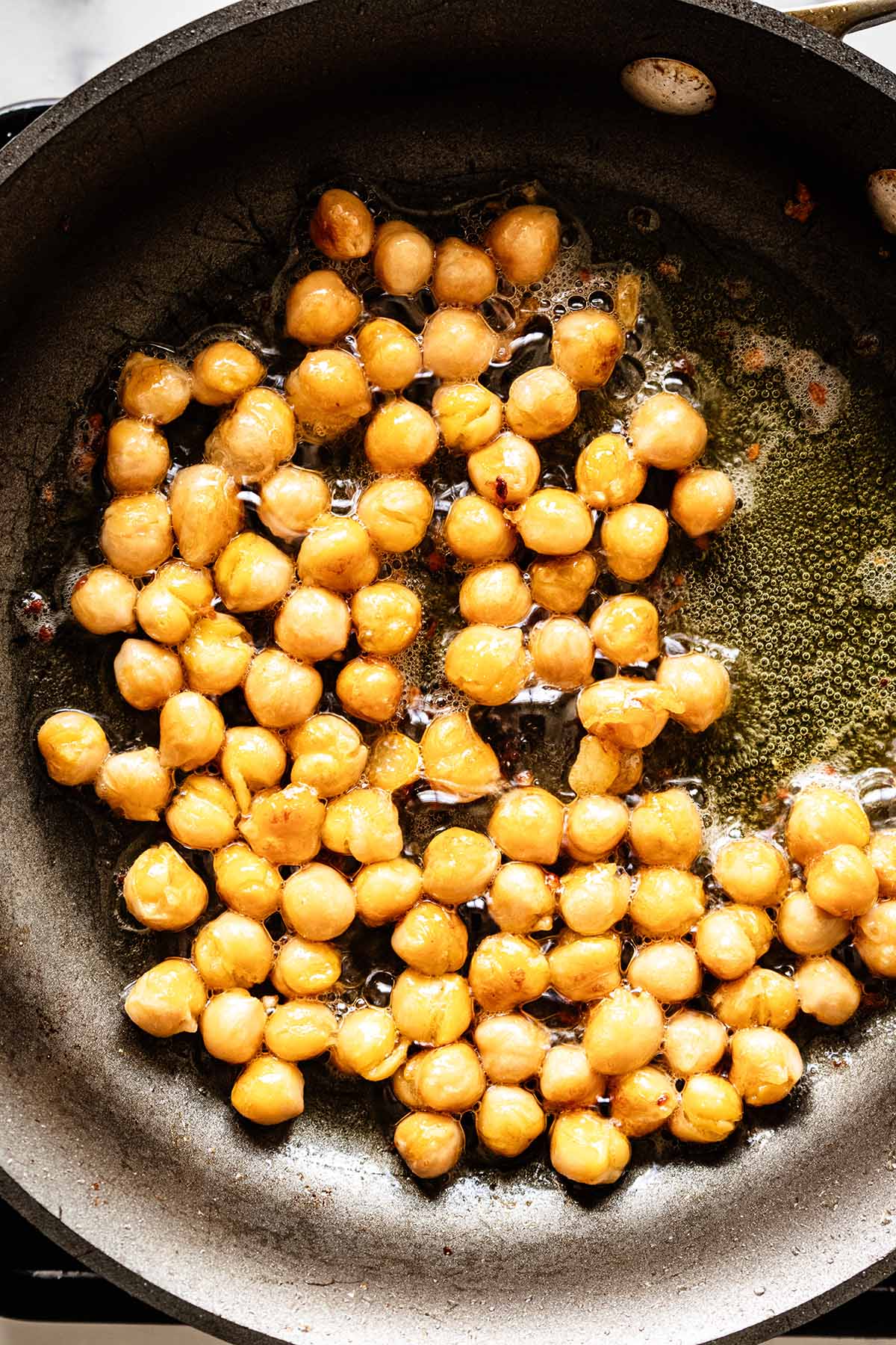 Overhead view of browned chickpeas in a skillet
