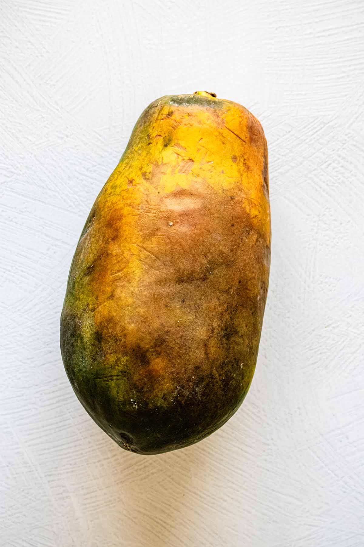 Whole ripe, unpeeled papaya on a countertop